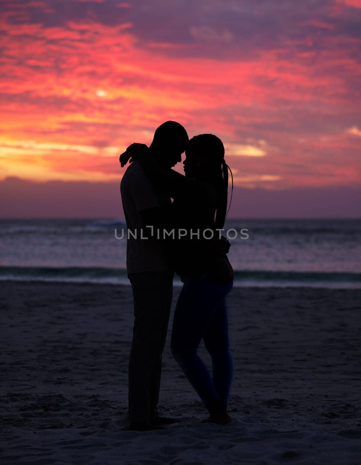 Couple, sunset and silhouette outdoor at the beach with love, care and commitment. Romantic man and woman hug or affectionate on vacation, holiday or nature travel adventure with sunrise sky on date.