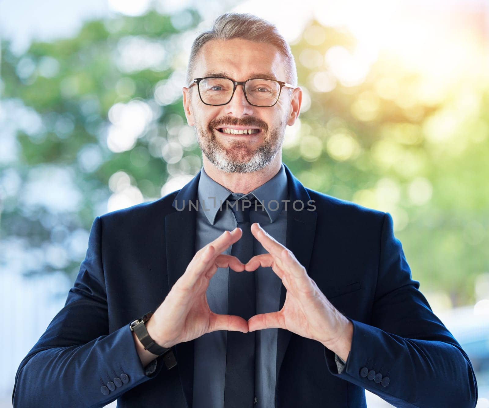 Face, business man and ceo with heart hands outdoor for trust, care and happy. Portrait, mature with love sign, smile for kindness or empathy, charity or gratitude, romance emoji or support by YuriArcurs