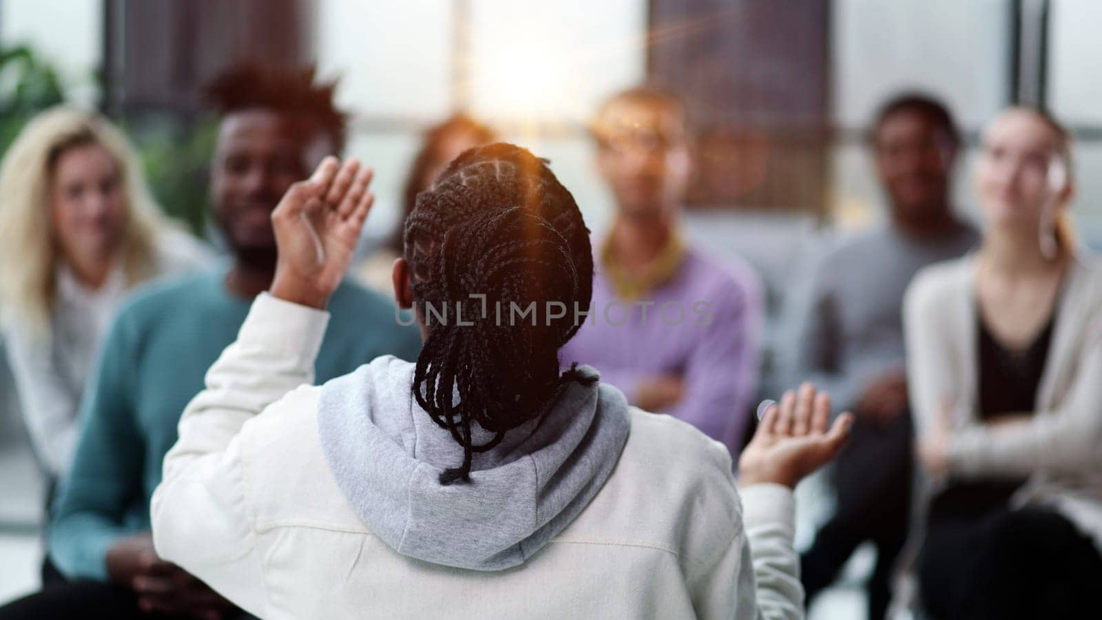 Young businessman sitting listening to trainer speaking to audience in trendy office