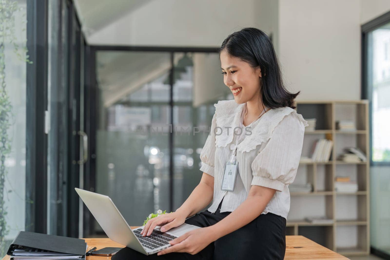 Portrait of a charming young woman businessman in the office siting holding a laptop n looking at the laptop.