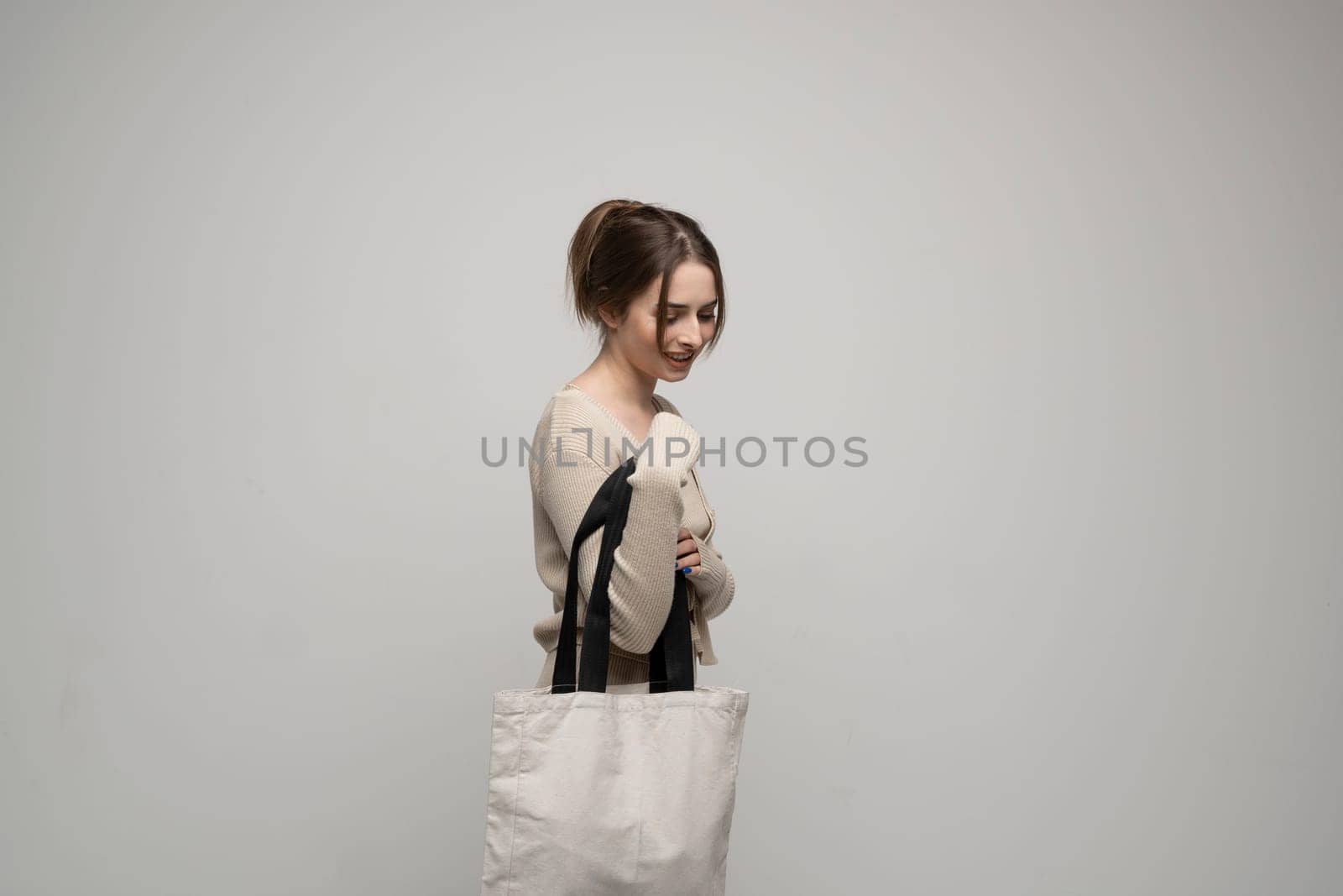 Young brunette woman with white cotton bag. Eco friendly lifestyle. Reuse, recylce, zero waste, No more plastic. by vovsht
