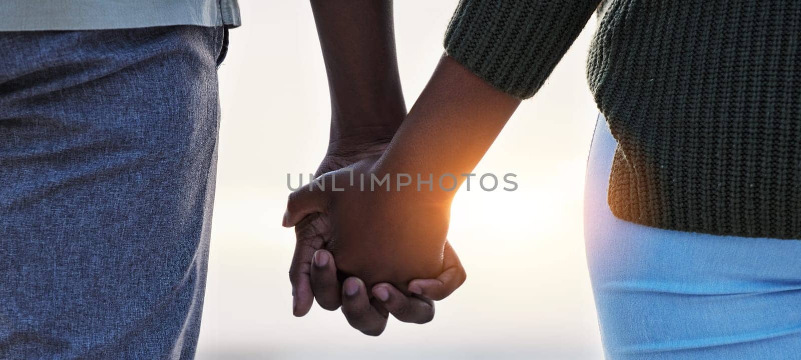 Holding hands, couple and love outdoor at the beach with care, trust and commitment. Closeup of a man and woman relax together on vacation, holiday or sunset travel adventure in nature for freedom.