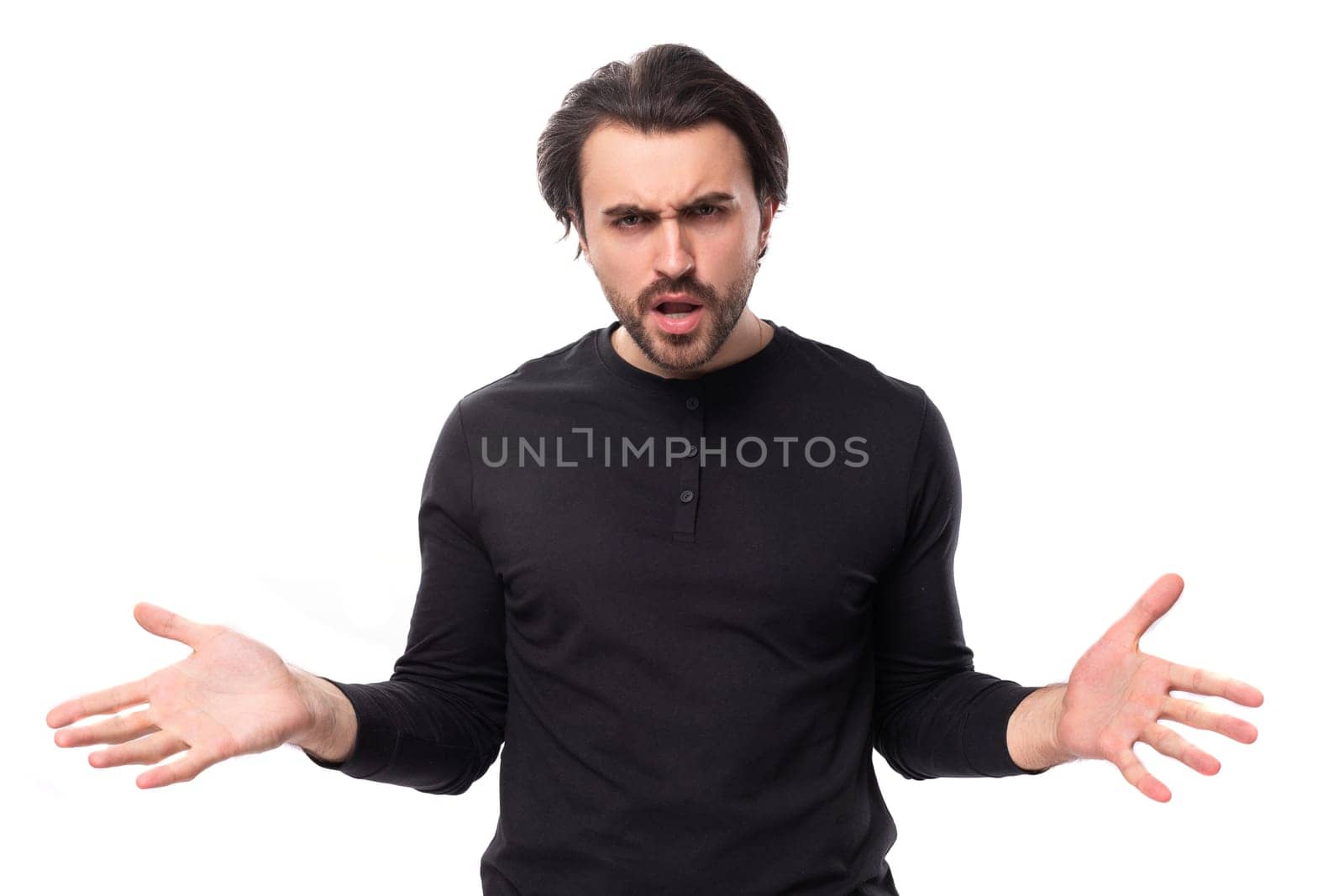 young confused pleasant brunette man in a black sweater on an isolated white background.