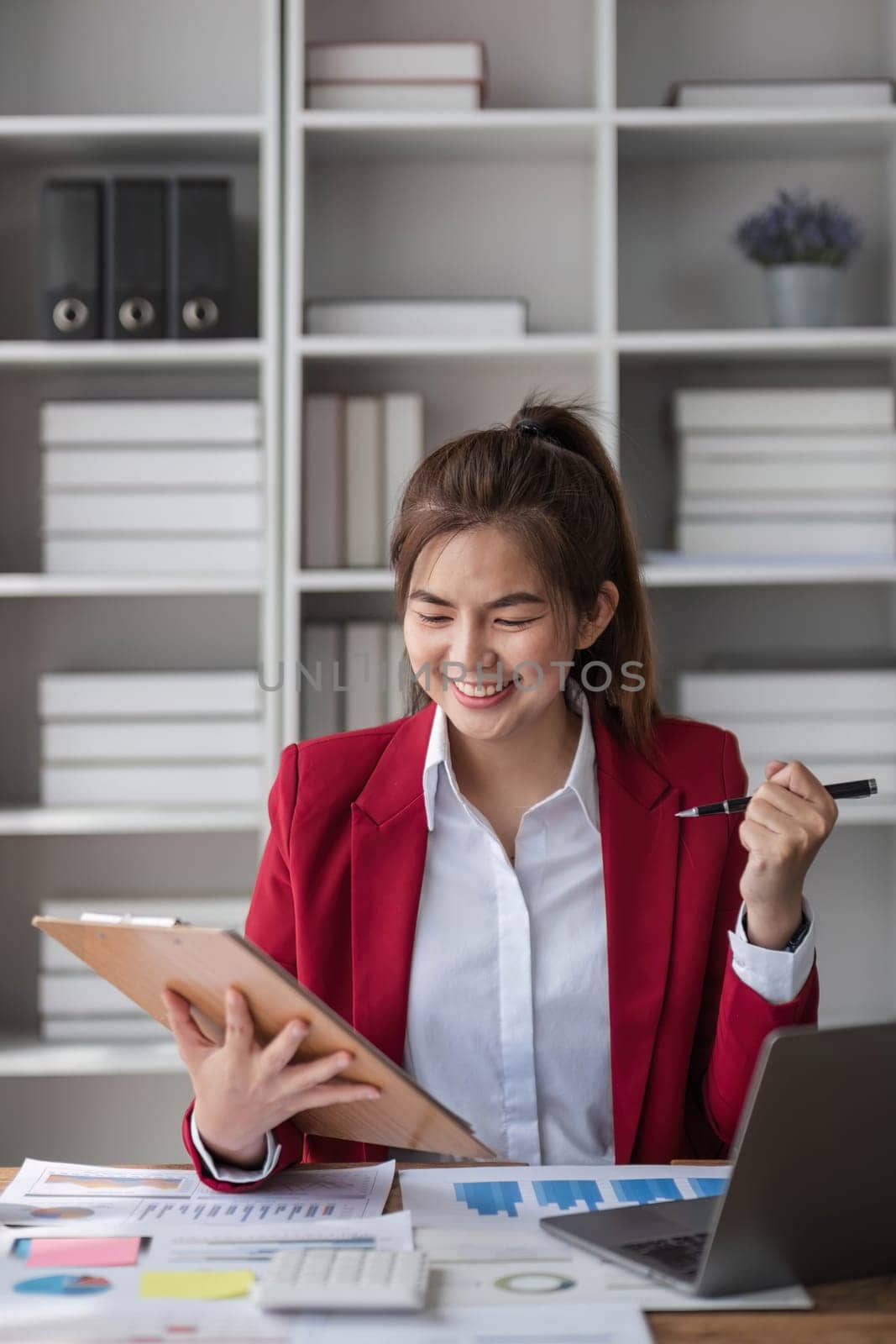 Beautiful Asian businesswoman celebrate while using laptop at office and showing delight. Startup small business and successful concept by wichayada