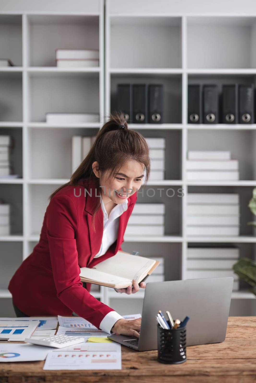 Beautiful Asian businesswoman celebrate while using laptop at office and showing delight. Startup small business and successful concept by wichayada