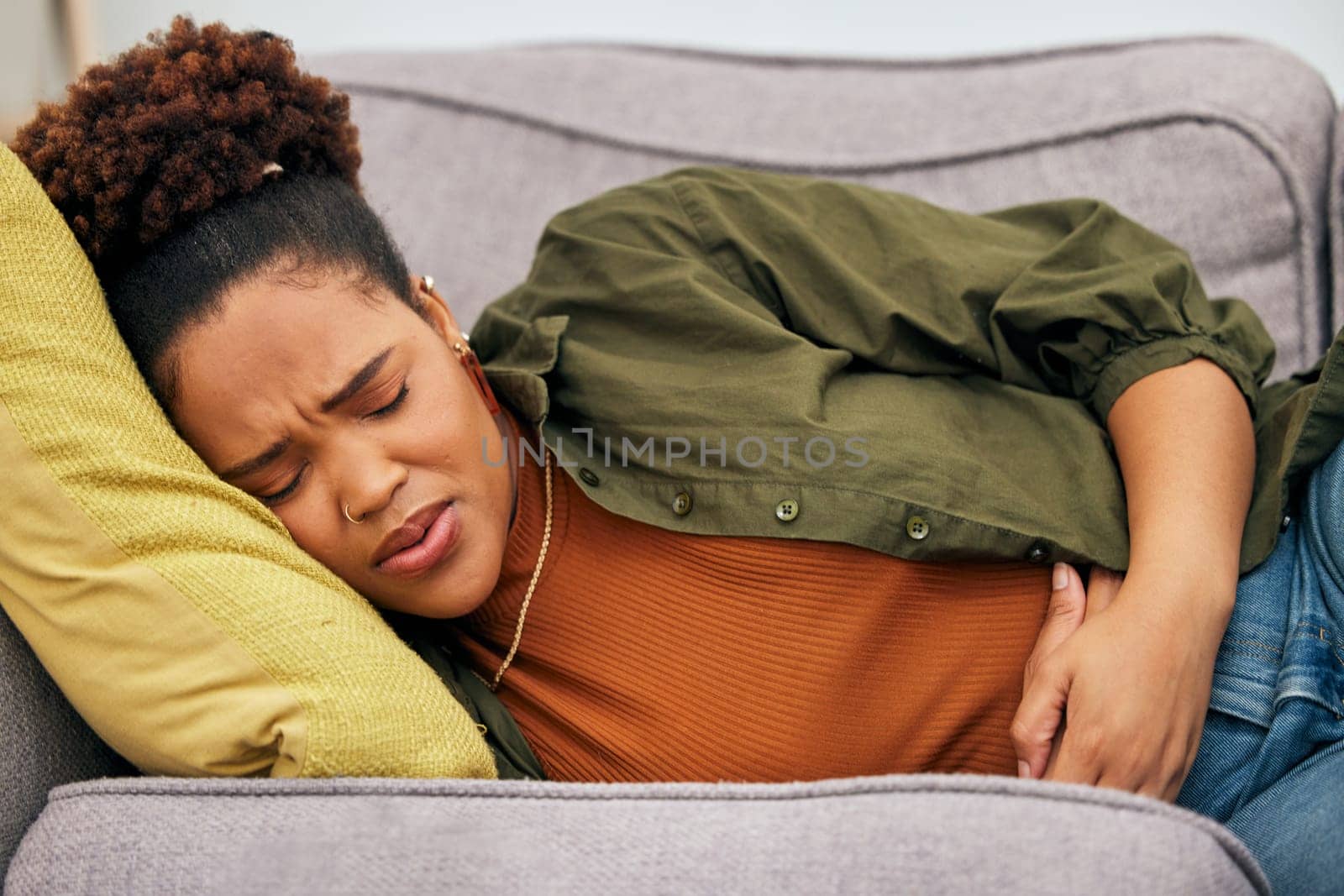 Sick woman, stomach pain and problem on sofa for ibs, health risk or nausea of gastric bloating, period cramps or virus. Black female person, menstruation or stress of constipation from endometriosis.