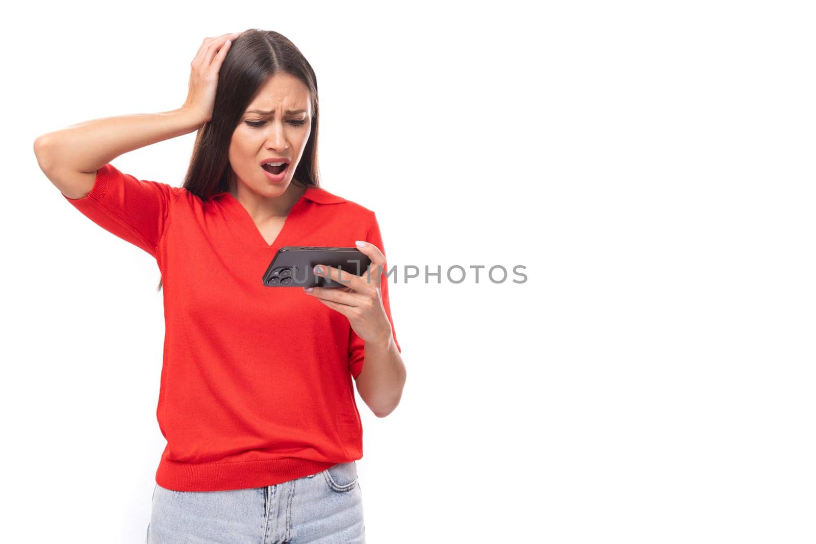 young european woman with black hair dressed in a red t-shirt watches video on the phone by TRMK
