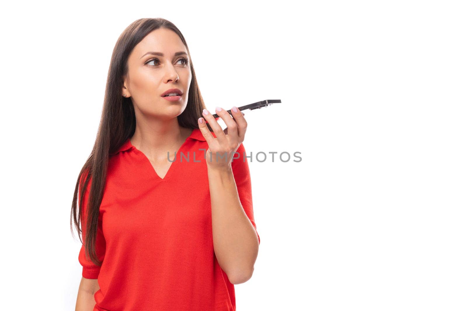 30 year old pretty caucasian woman with straight dark hair dressed in a red short sleeve shirt uses a smartphone.