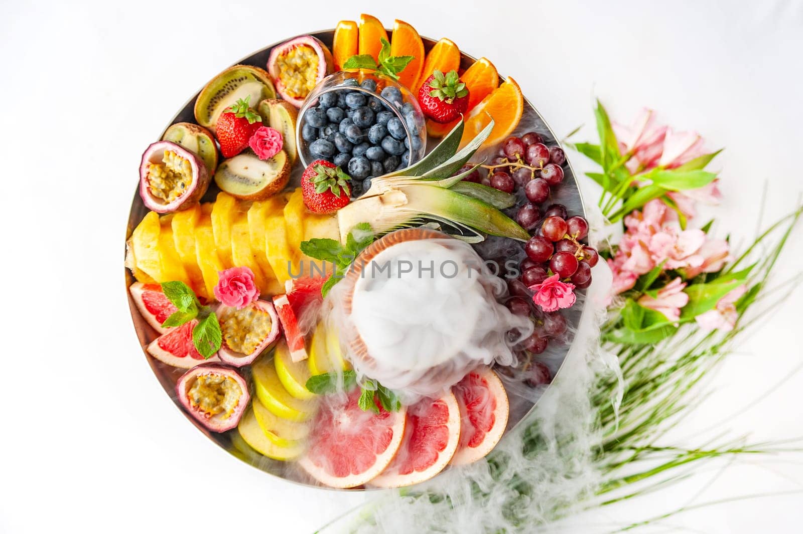 Raw fruits and berries assortment platter on the plate, on the white table