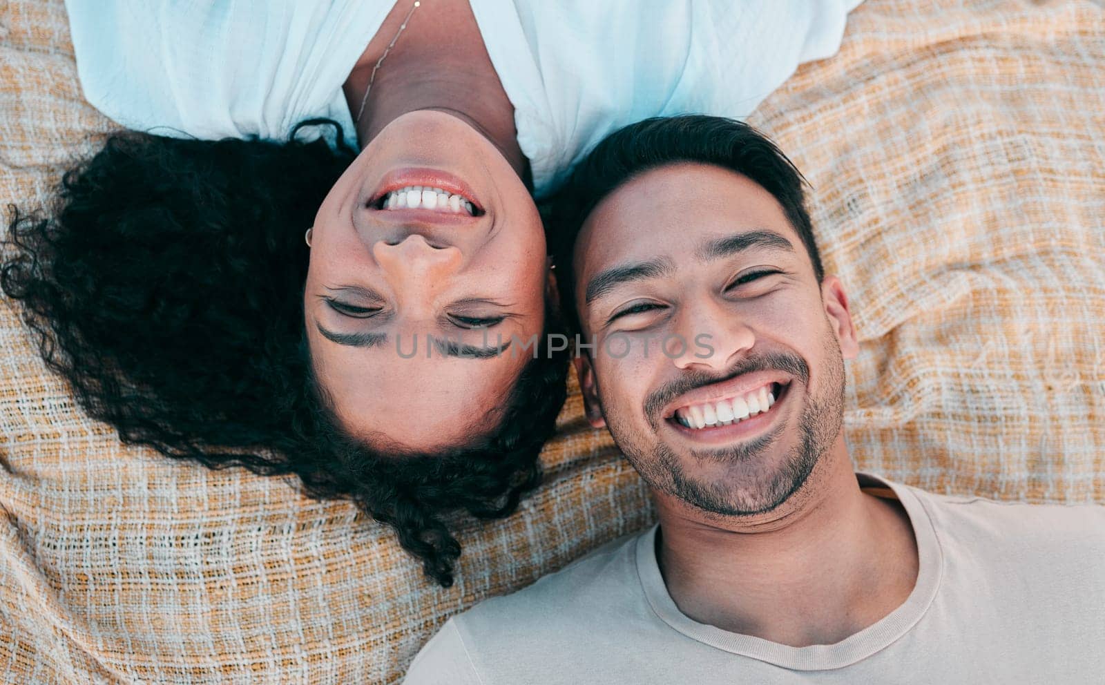 Portrait, picnic and smile with a couple on a blanket from above, lying down on the ground while on a date. Face, love or happy with a man and woman bonding together for romance on valentines day by YuriArcurs