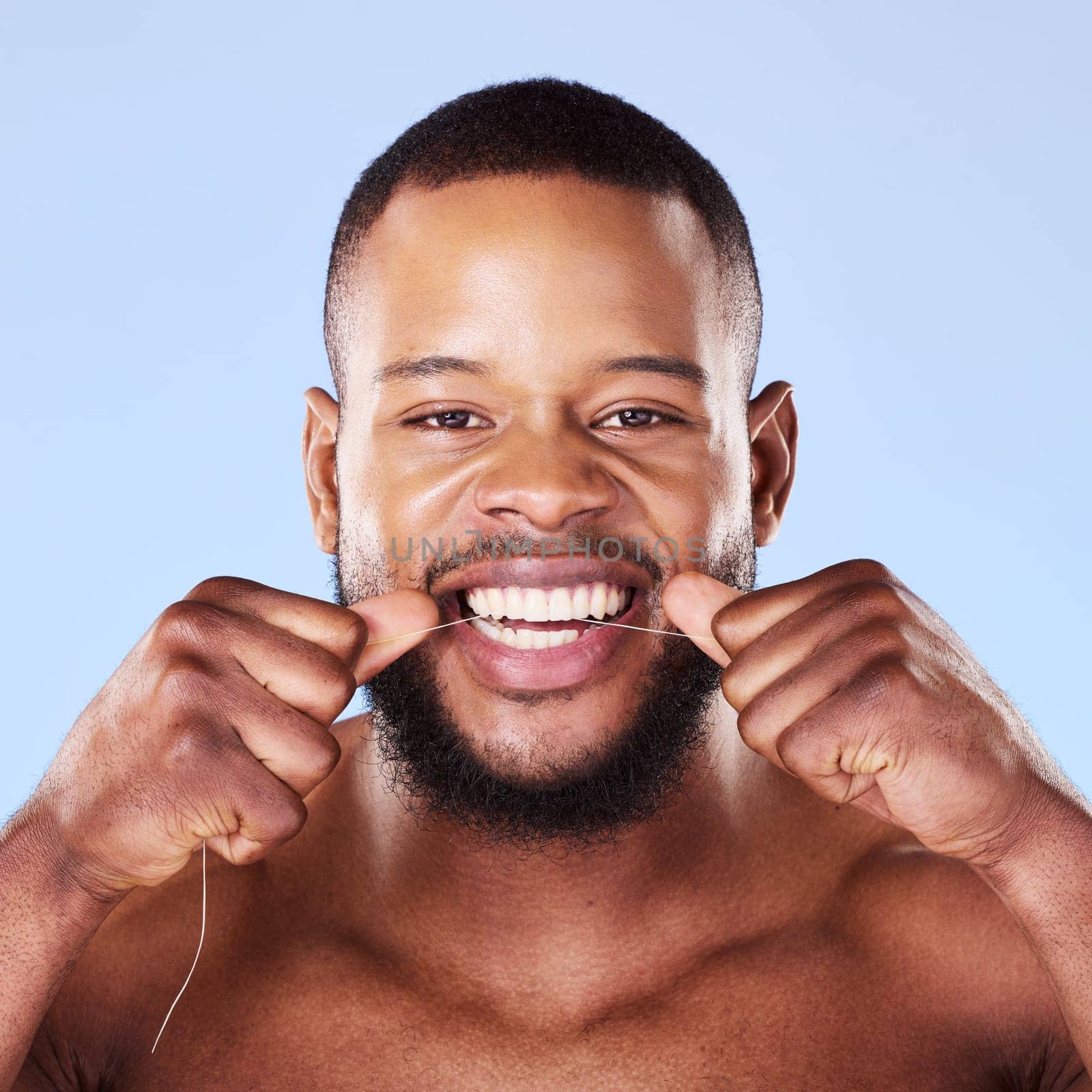 Portrait, black man and floss teeth in studio, healthy dental care or gum gingivitis. Face of male model cleaning mouth with oral thread for fresh breath, tooth cosmetics or plaque on blue background by YuriArcurs