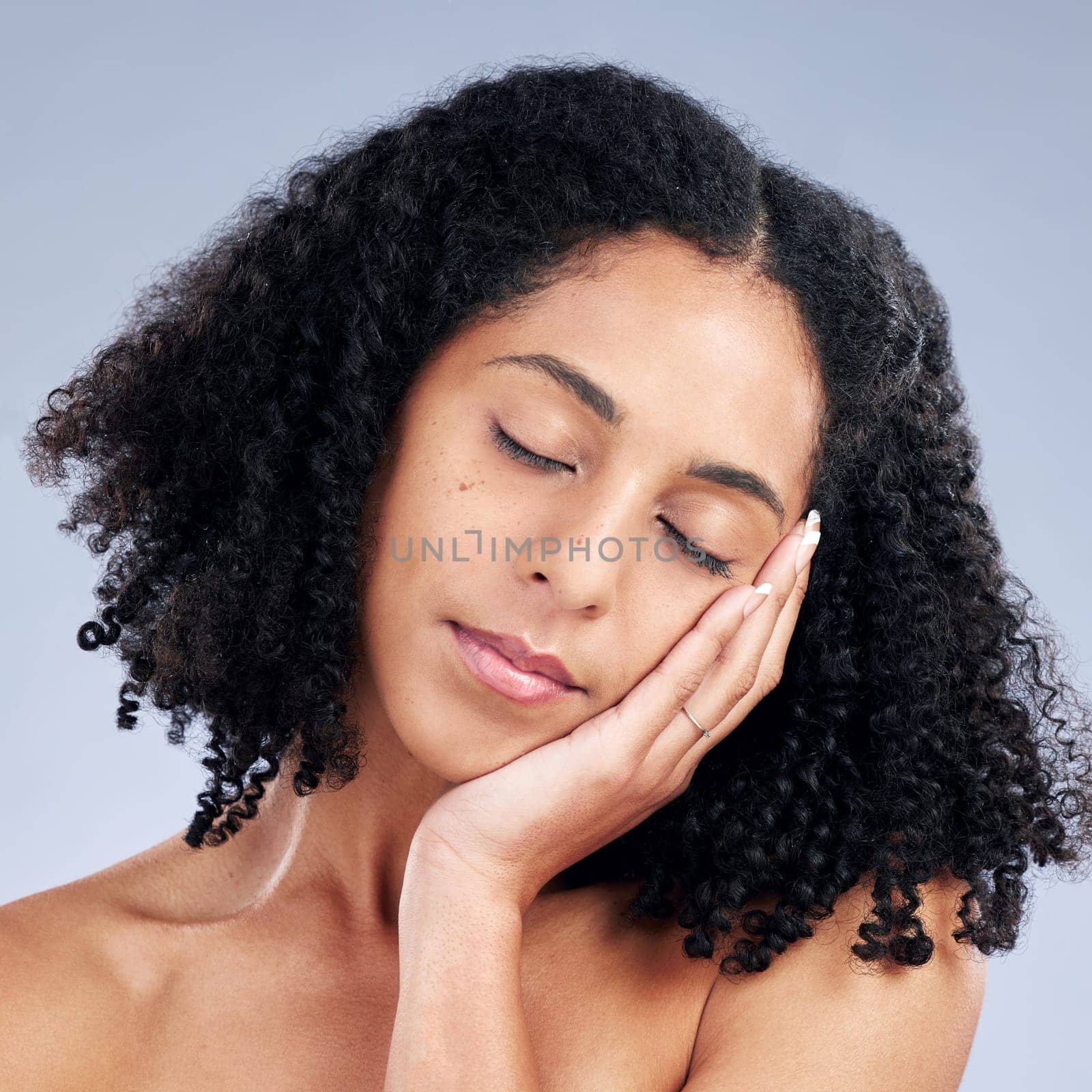 Woman touching face, beauty and natural skincare, cosmetics and curly hair on studio background. Haircare, wellness and self care, healthy skin glow and peace with female model and dermatology.