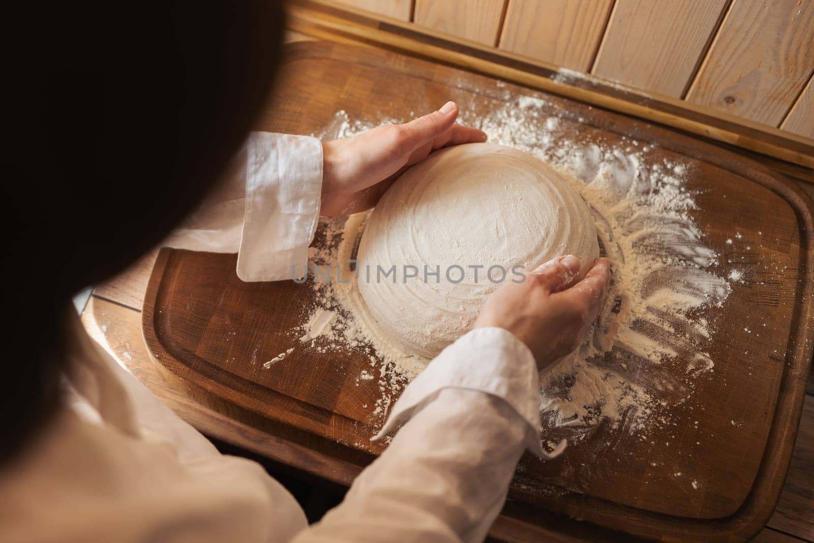 Female baker rubbing flour to the bread dough before baking it in the oven