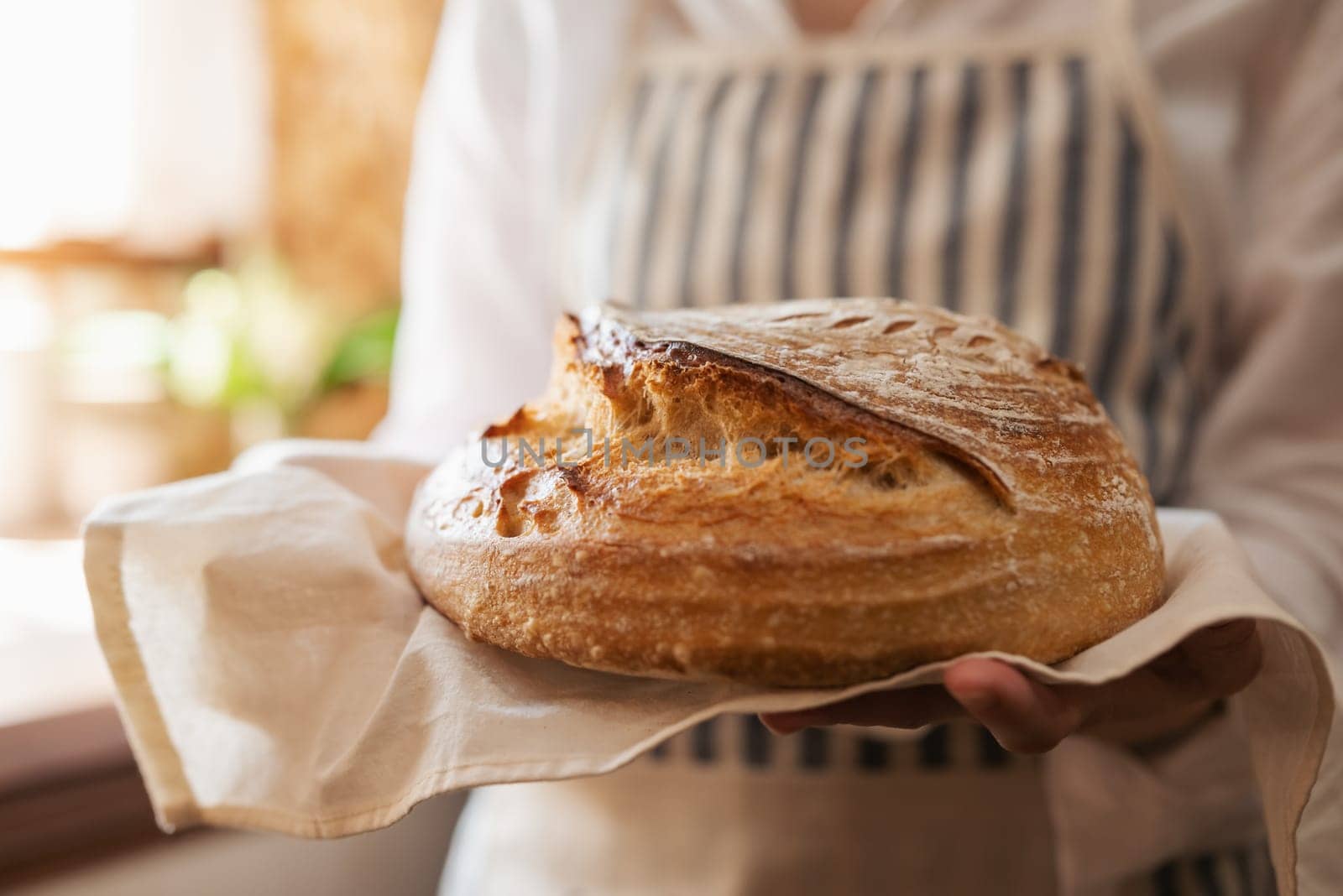 Self made bread in hands of a girl standing in kitchen