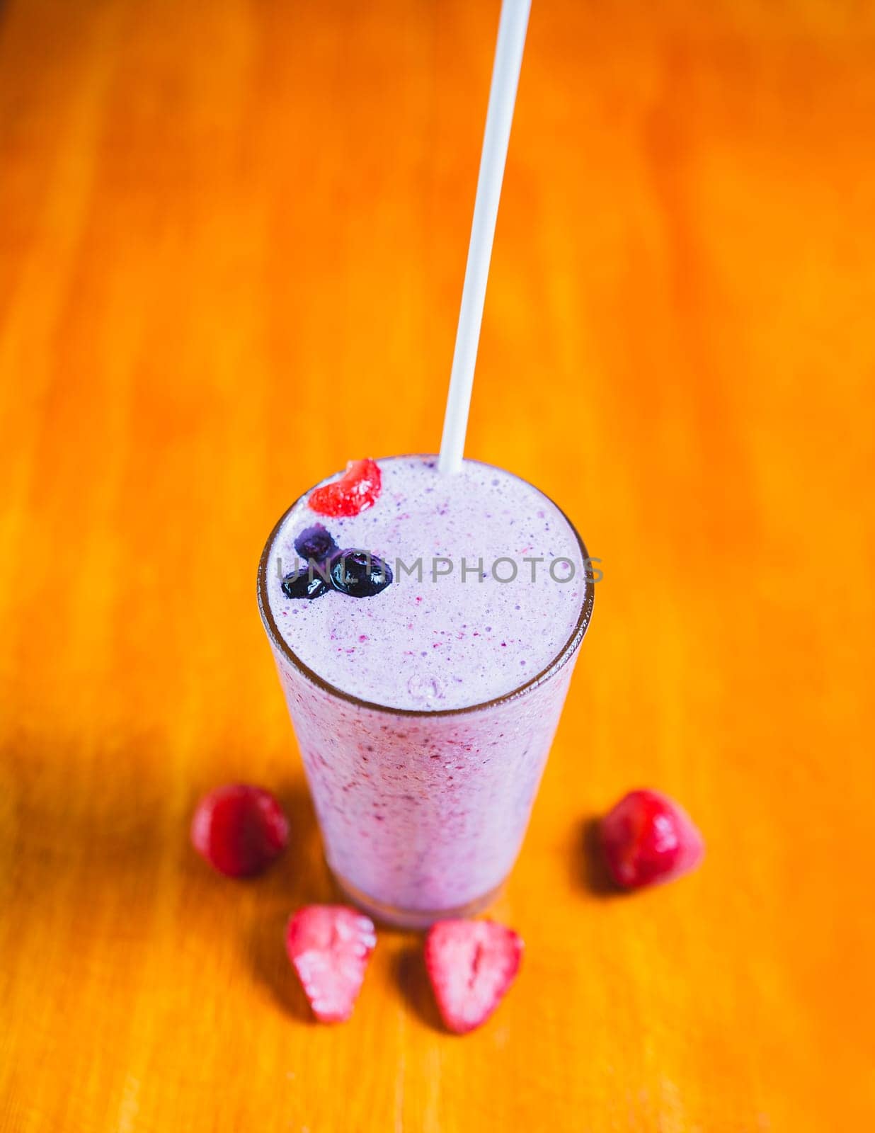 Strawberry smoothie with blueberry on wooden background. Strawberry milkshake on wooden table