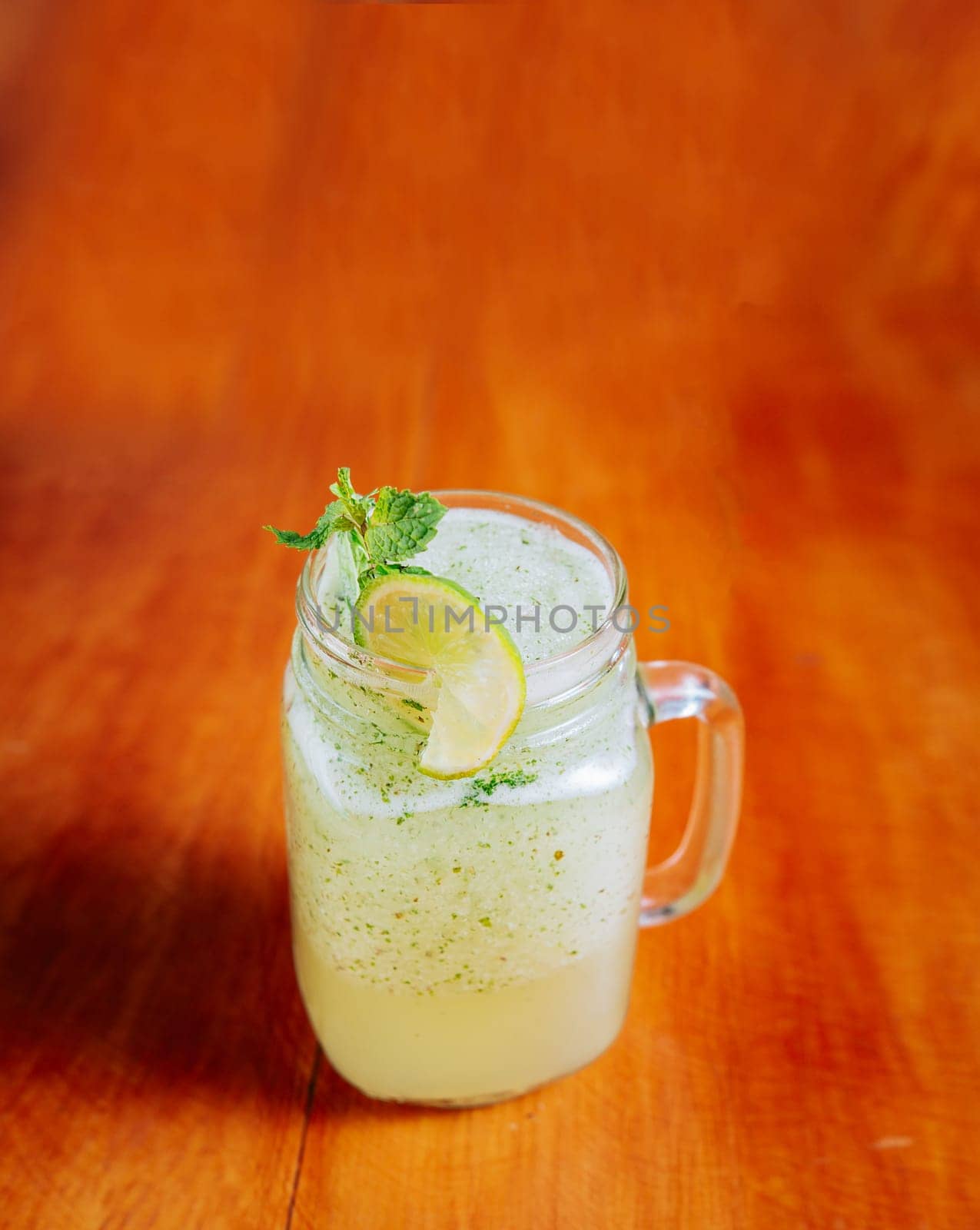 Refreshing lemonade with mint on wooden table. Lemonade drink on wooden background by isaiphoto