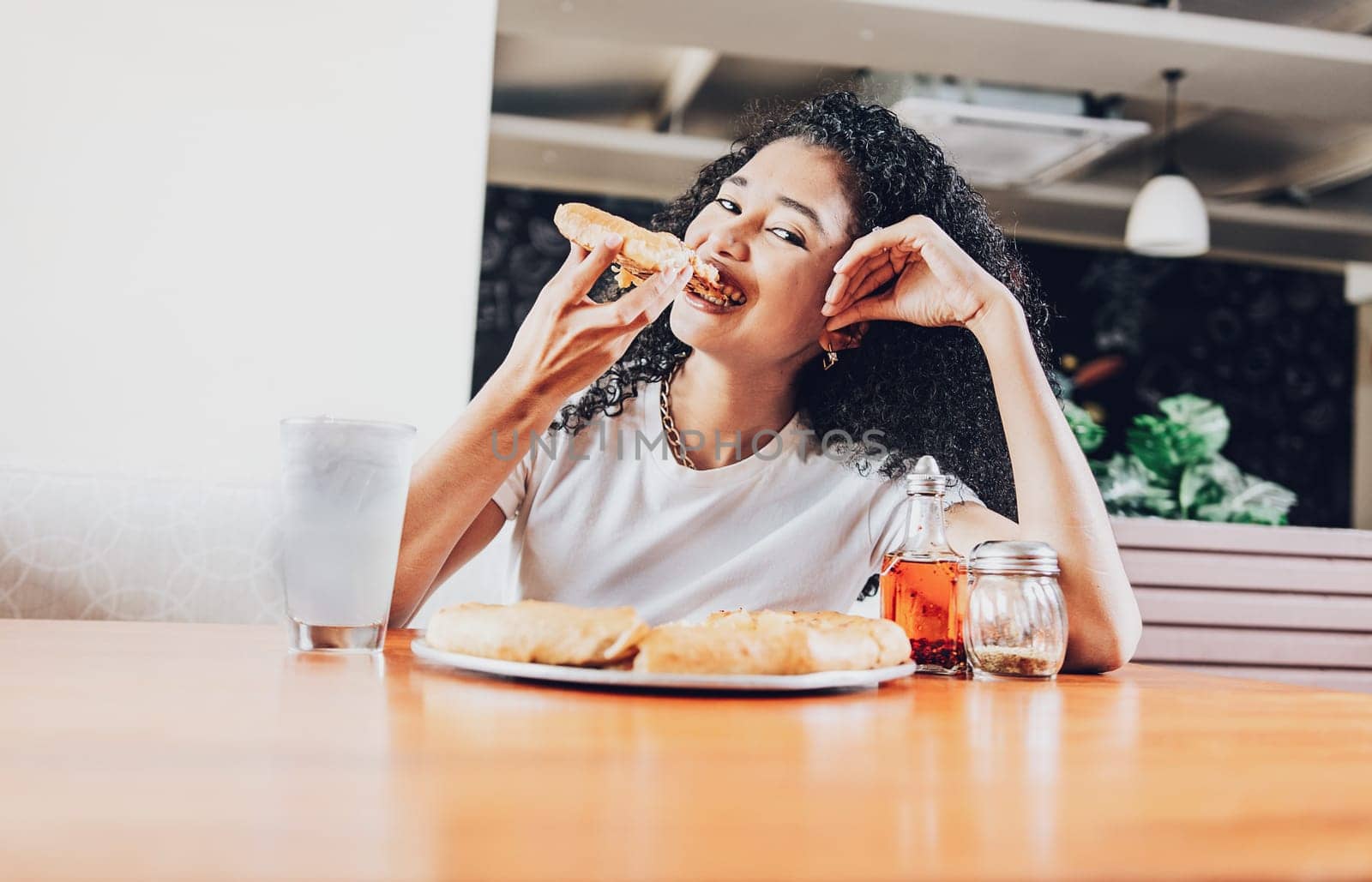 Smiling afro-haired woman enjoying a pizza in a restaurant. Happy afro hair woman eating pizza in a restaurant by isaiphoto