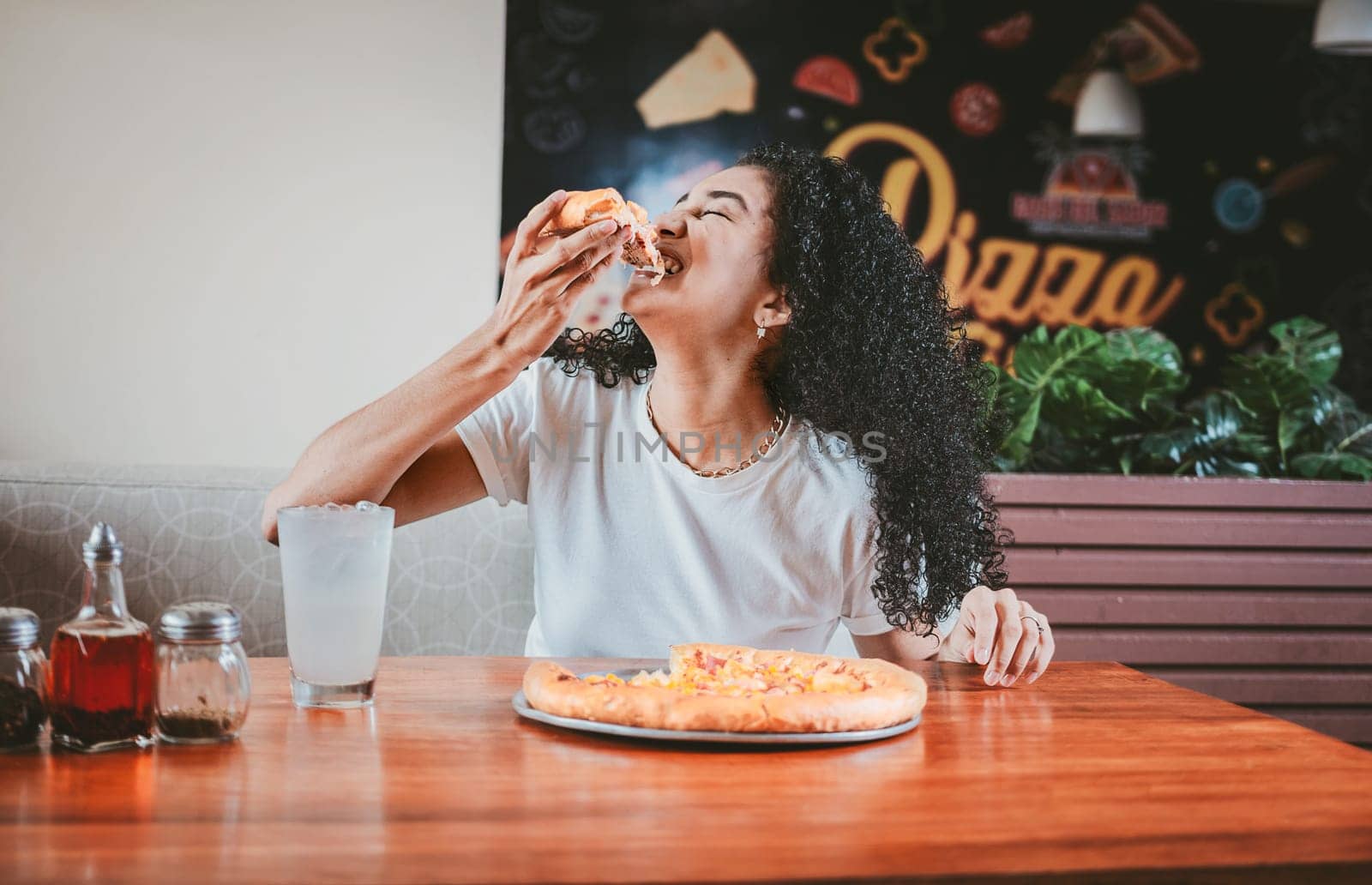 Lifestyle of afro-haired woman enjoying a pizza in a restaurant. Happy afro hair woman eating pizza in a restaurant by isaiphoto