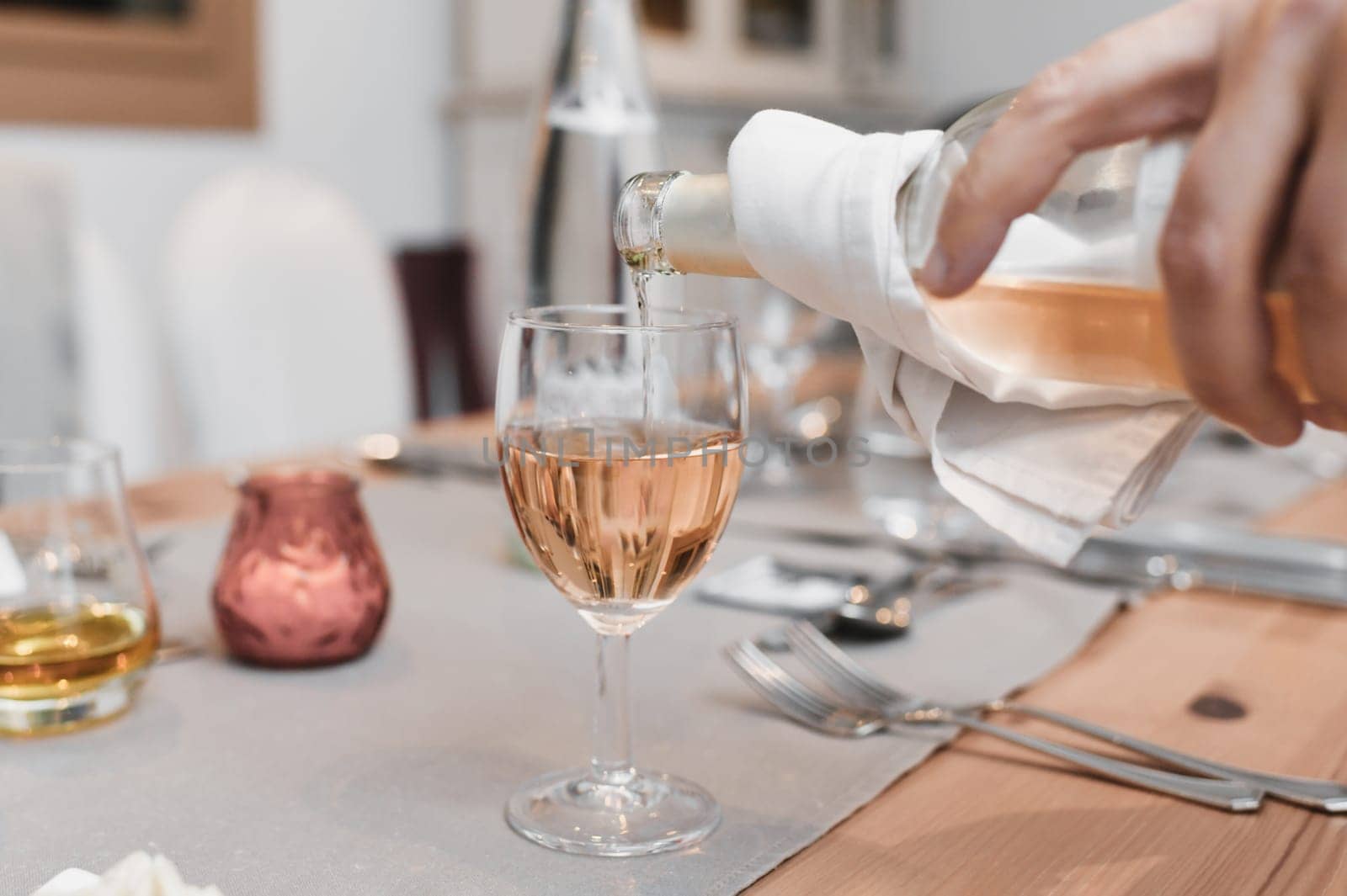 The waiter pours the pink french wine into the glass