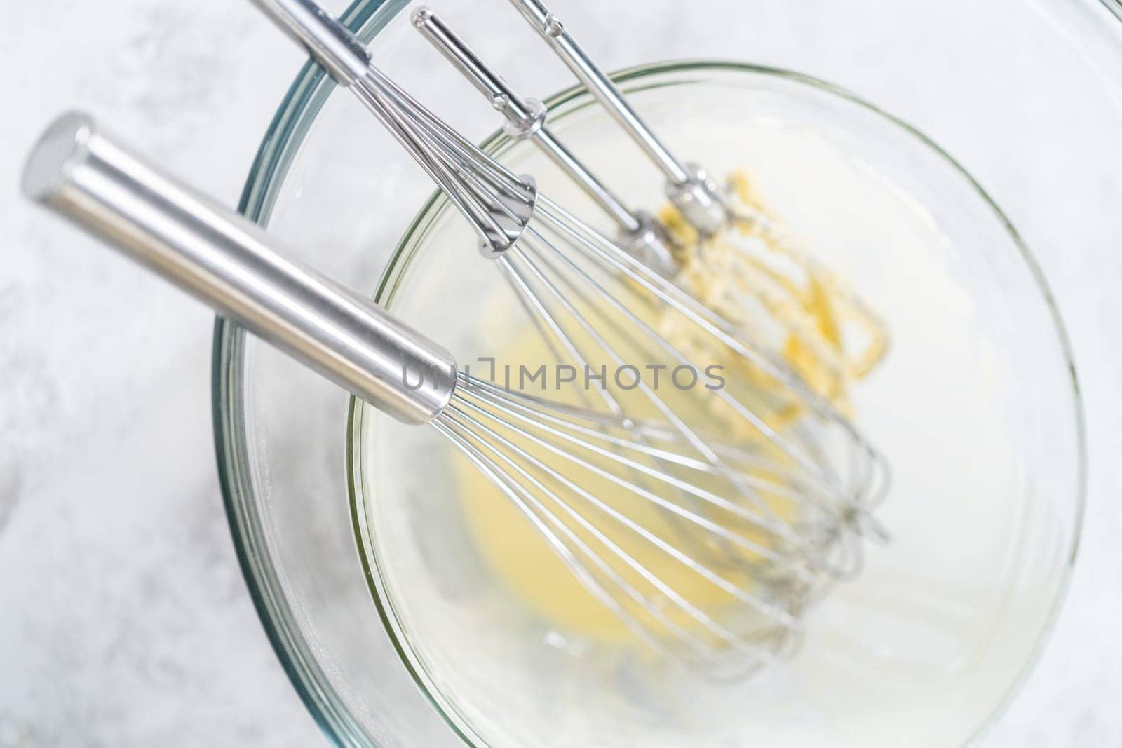 Dirty whisks in a glass mixing bowl after baking a cake.