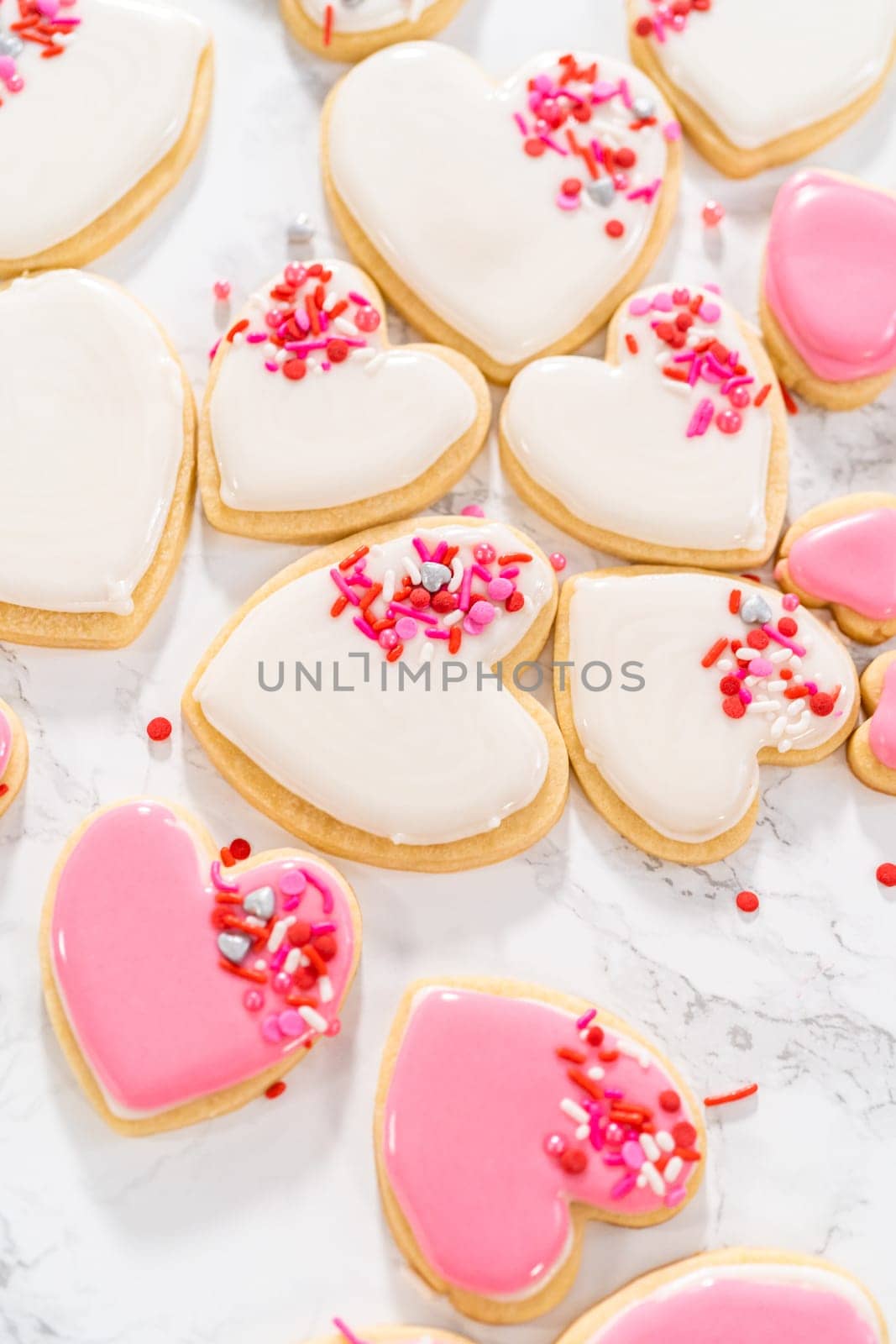 Decorating heart-shaped sugar cookies with pink and white royal icing for Valentine's Day.