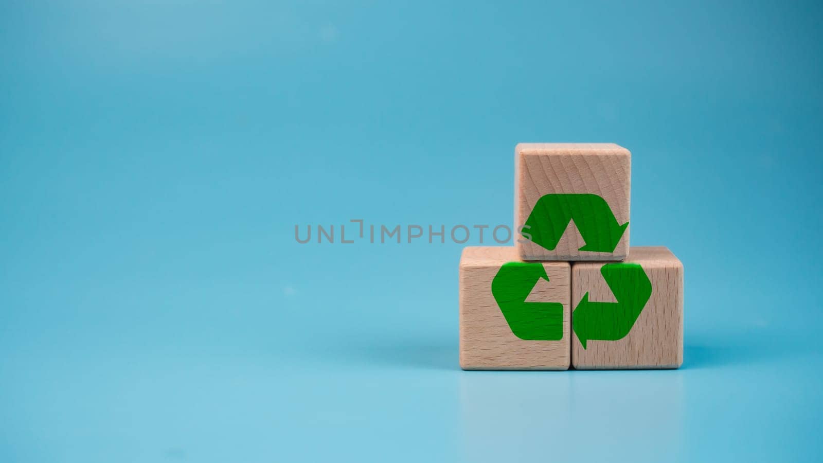 Stacked wooden blocks with green recycle symbol. Recycling concept. by Unimages2527