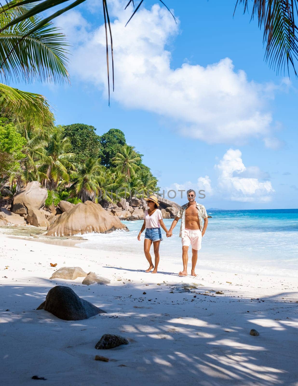 Anse Lazio Praslin Seychelles, a young couple of men and women on a tropical beach during vacation by fokkebok