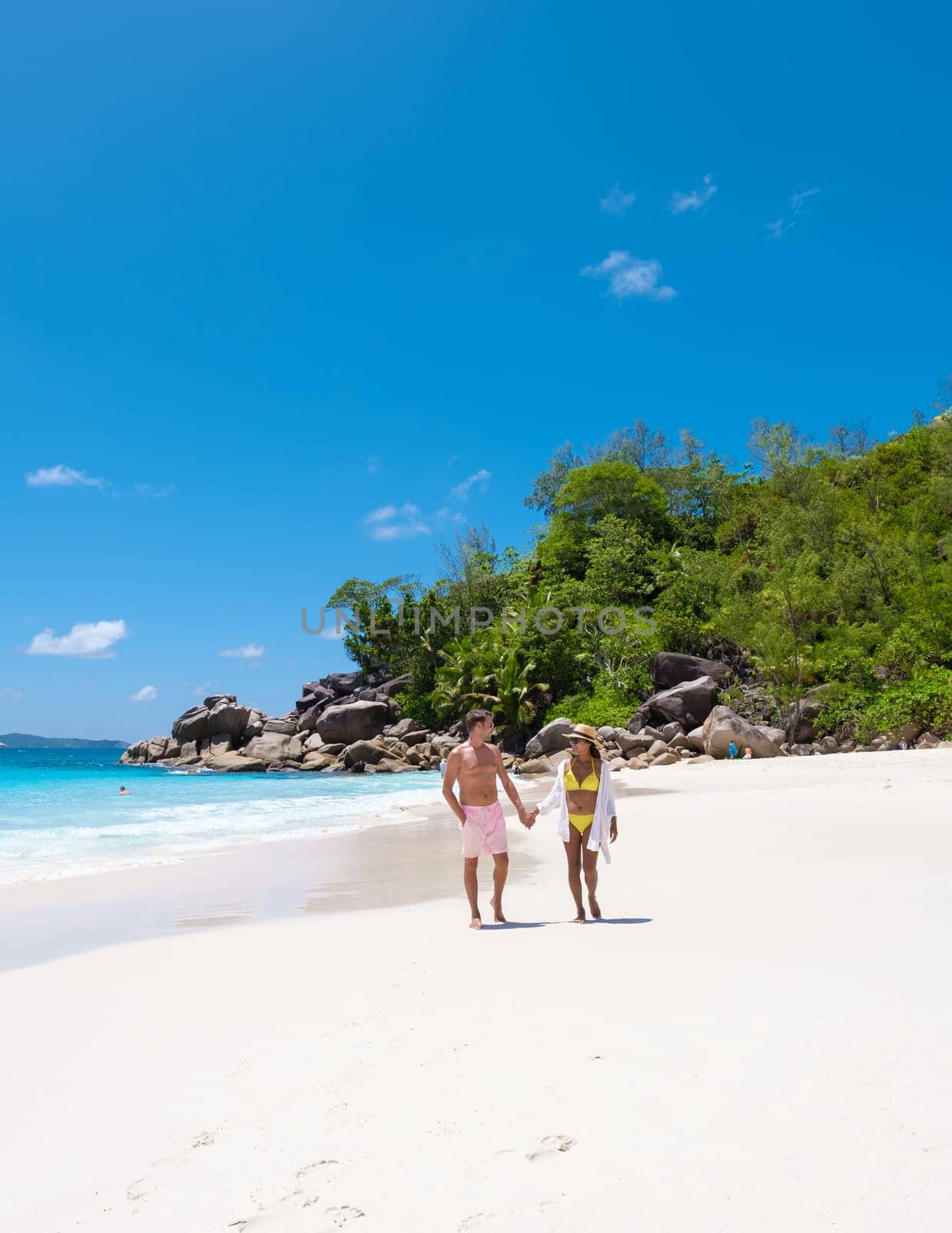 Anse Lazio Praslin Seychelles is a young couple of men and women on a tropical beach during a luxury vacation there. Tropical beach Anse Lazio Praslin Seychelles tropical Islands