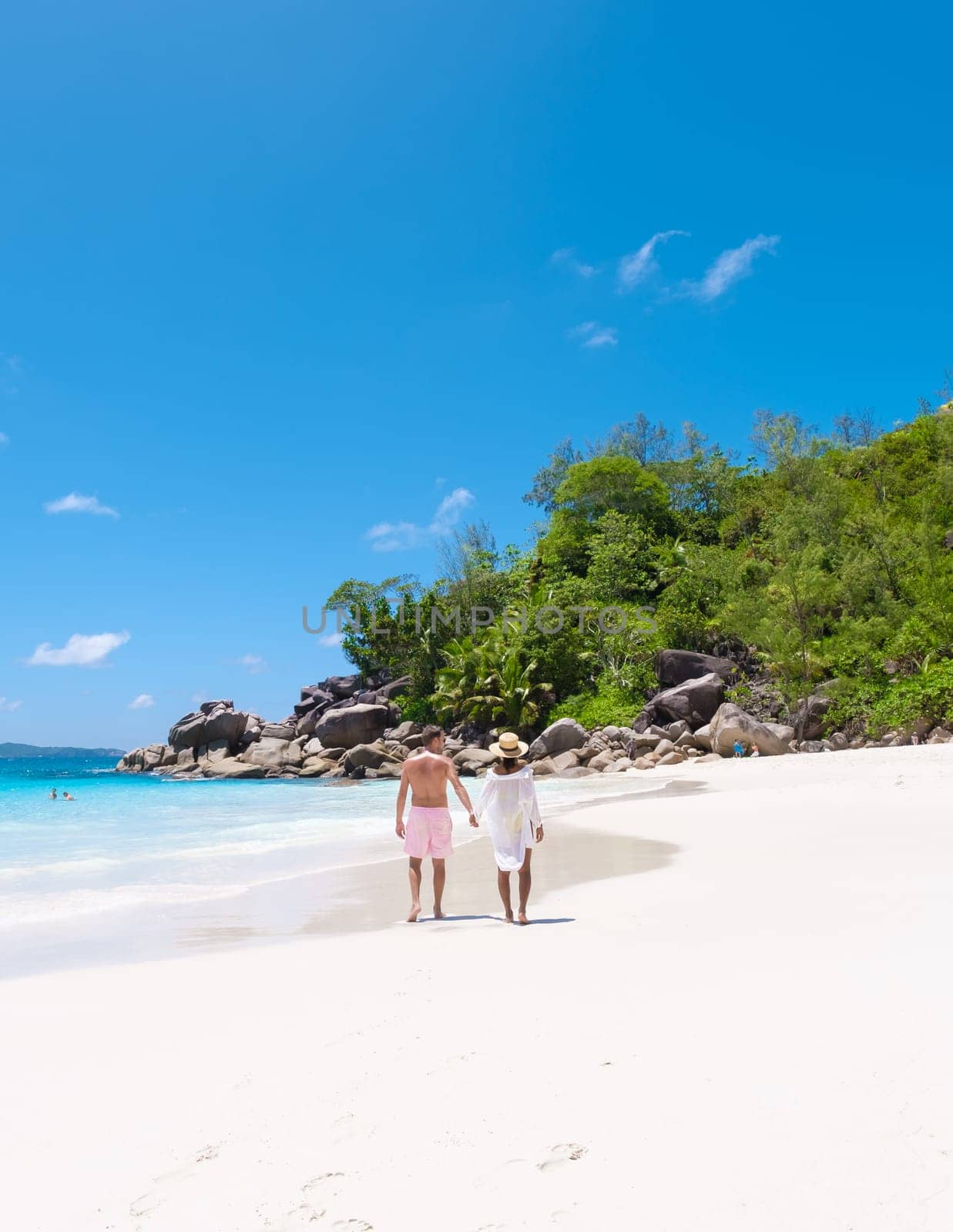 Anse Lazio Praslin Seychelles a young couple of men and women on a tropical beach during a luxury vacation there. Tropical beach Anse Lazio Praslin Seychelles Islands on a sunny day with a blue sky