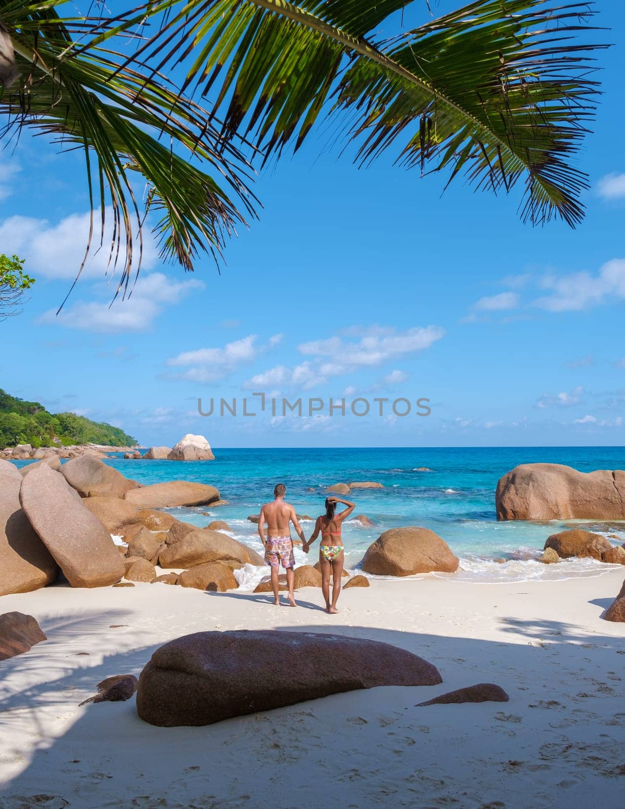 Anse Lazio Praslin Seychelles a young couple of men and women on a tropical beach during a luxury vacation there. Tropical beach Anse Lazio Praslin Seychelles Islands on a sunny day with a blue sky