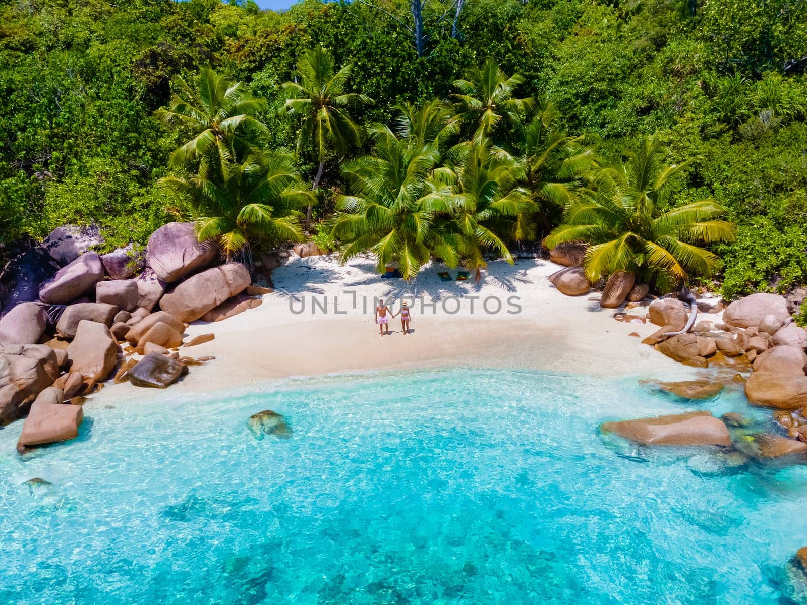 Anse Lazio Praslin Seychelles a young couple of men and women on a tropical beach during a luxury vacation there. Tropical beach Anse Lazio Praslin Seychelles Islands on a sunny day with a blue sky