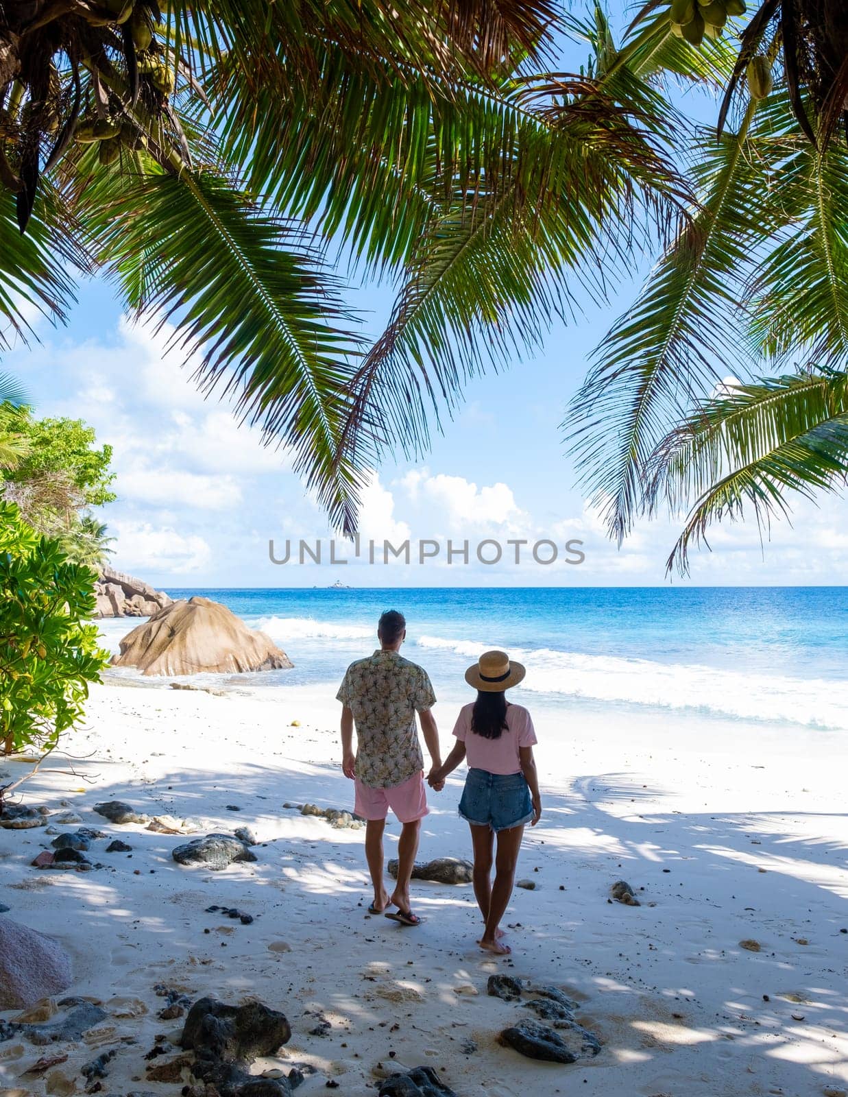 Anse Lazio Praslin Seychelles is a young couple of men and women on a tropical beach during a luxury vacation there. Tropical beach Anse Lazio Praslin Seychelles Islands