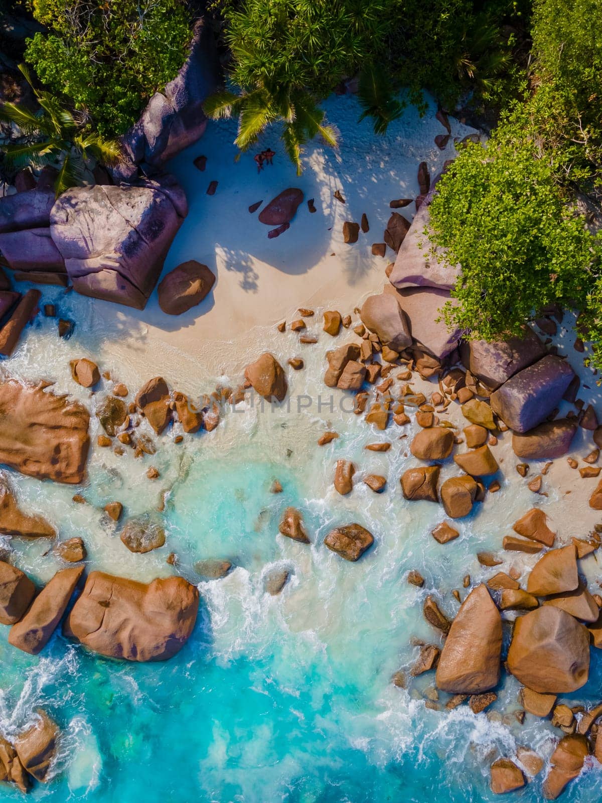 Anse Lazio Praslin Seychelles, a young couple of men and women on a tropical beach during a luxury vacation at the Seychelles. Tropical beach Anse Lazio Praslin Seychelles Islands drone aerial view