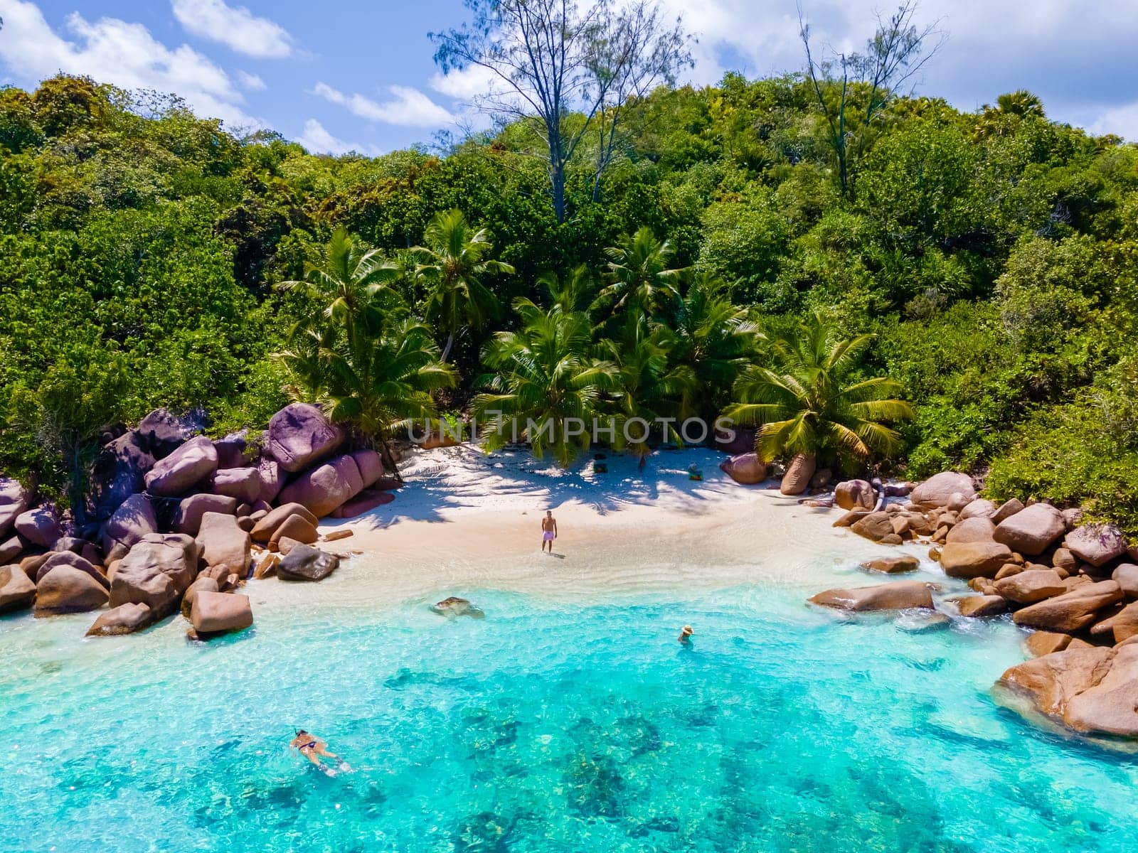 Anse Lazio Praslin Seychelles, a young couple of men and women on a tropical beach during a luxury vacation at the Seychelles. Tropical beach Anse Lazio Praslin Seychelles Islands drone view