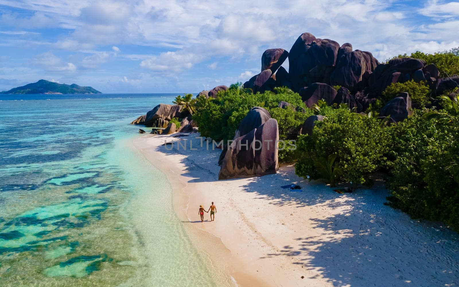 Anse Source d'Argent, La Digue Seychelles, a young couple of men and women on a tropical beach during a luxury vacation in Seychelles. drone view from above at a tropical beach