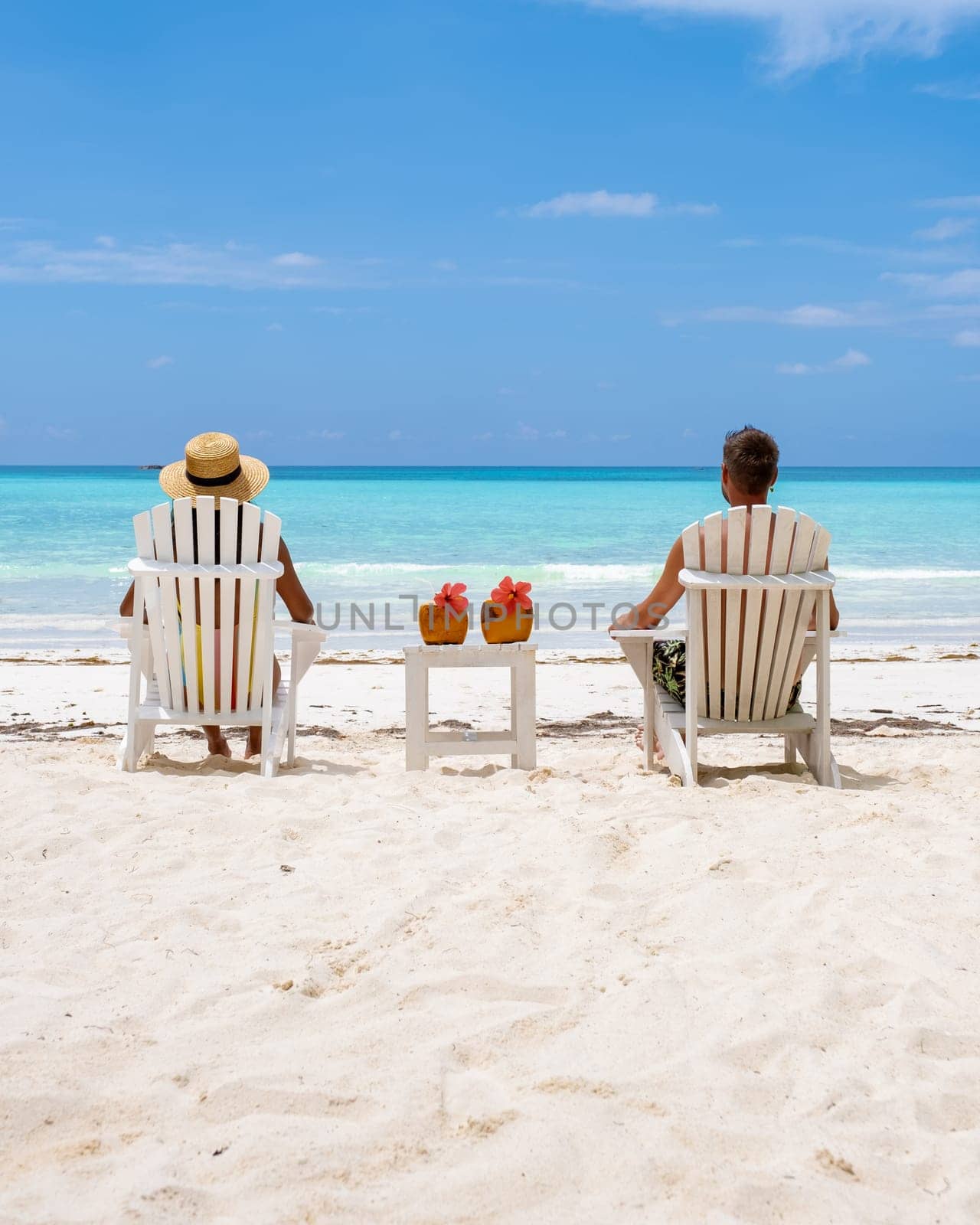 couple men and women on the beach with a coconut drink at Praslin Island Seychelles. a tropical island with a white beach and blue ocean, the beach of Anse Volbert Seychelles.