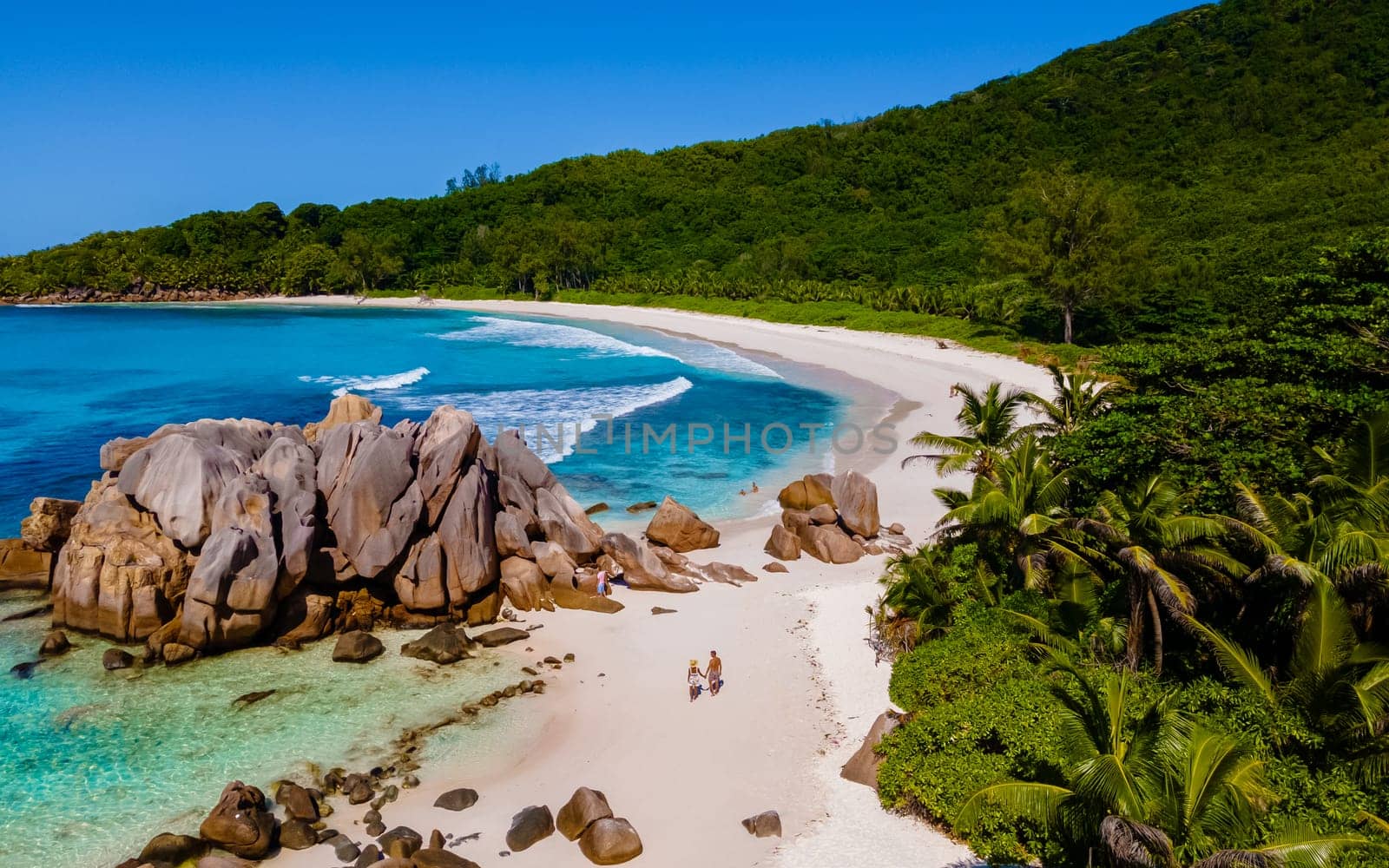 Anse Cocos La Digue Seychelles, a young couple of men and women on a tropical beach during a luxury vacation in Seychelles. Tropical beach Anse Cocos La Digue Seychelles with a blue ocean