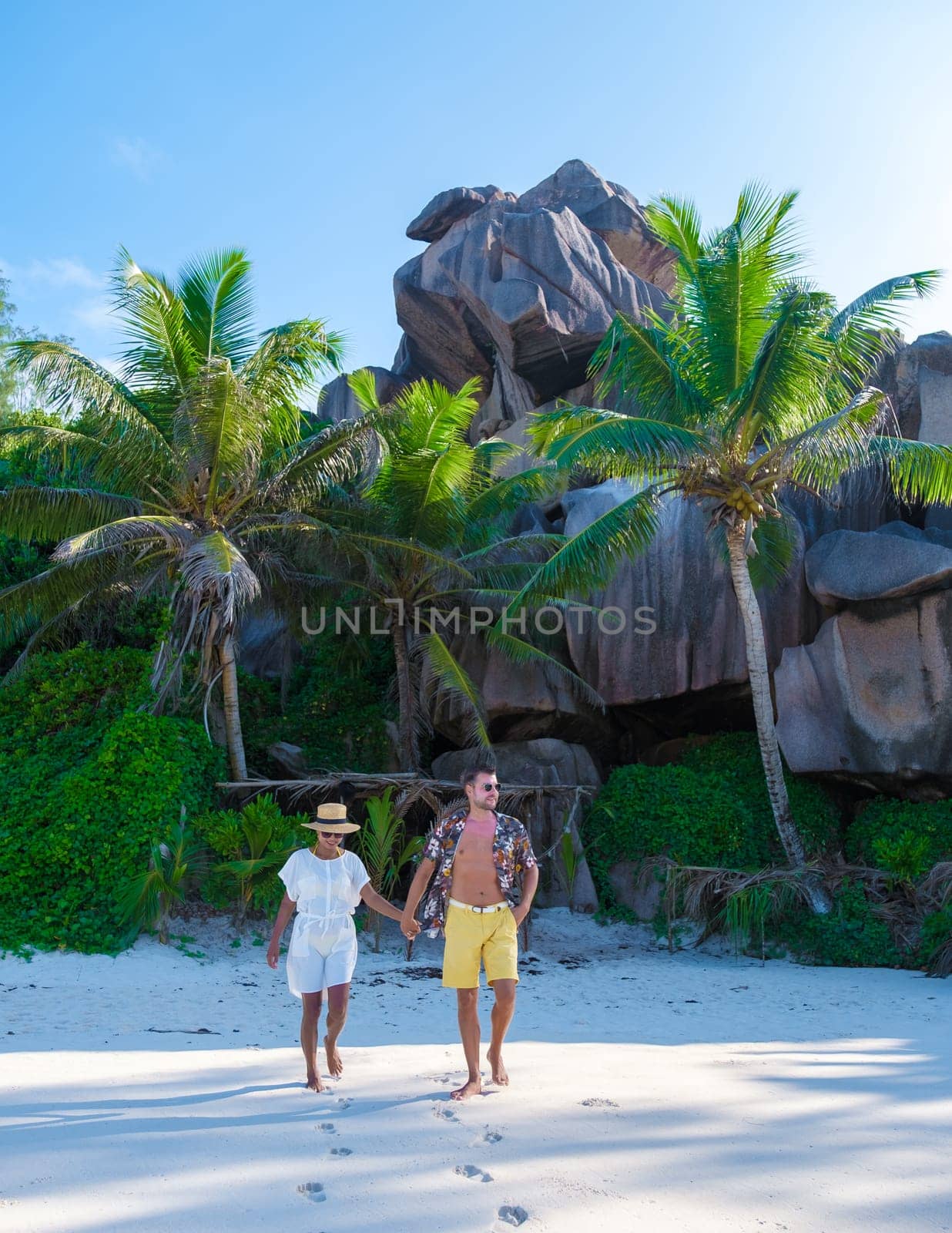 Anse Cocos La Digue Seychelles, a young couple of men and women on a tropical beach during vacation by fokkebok