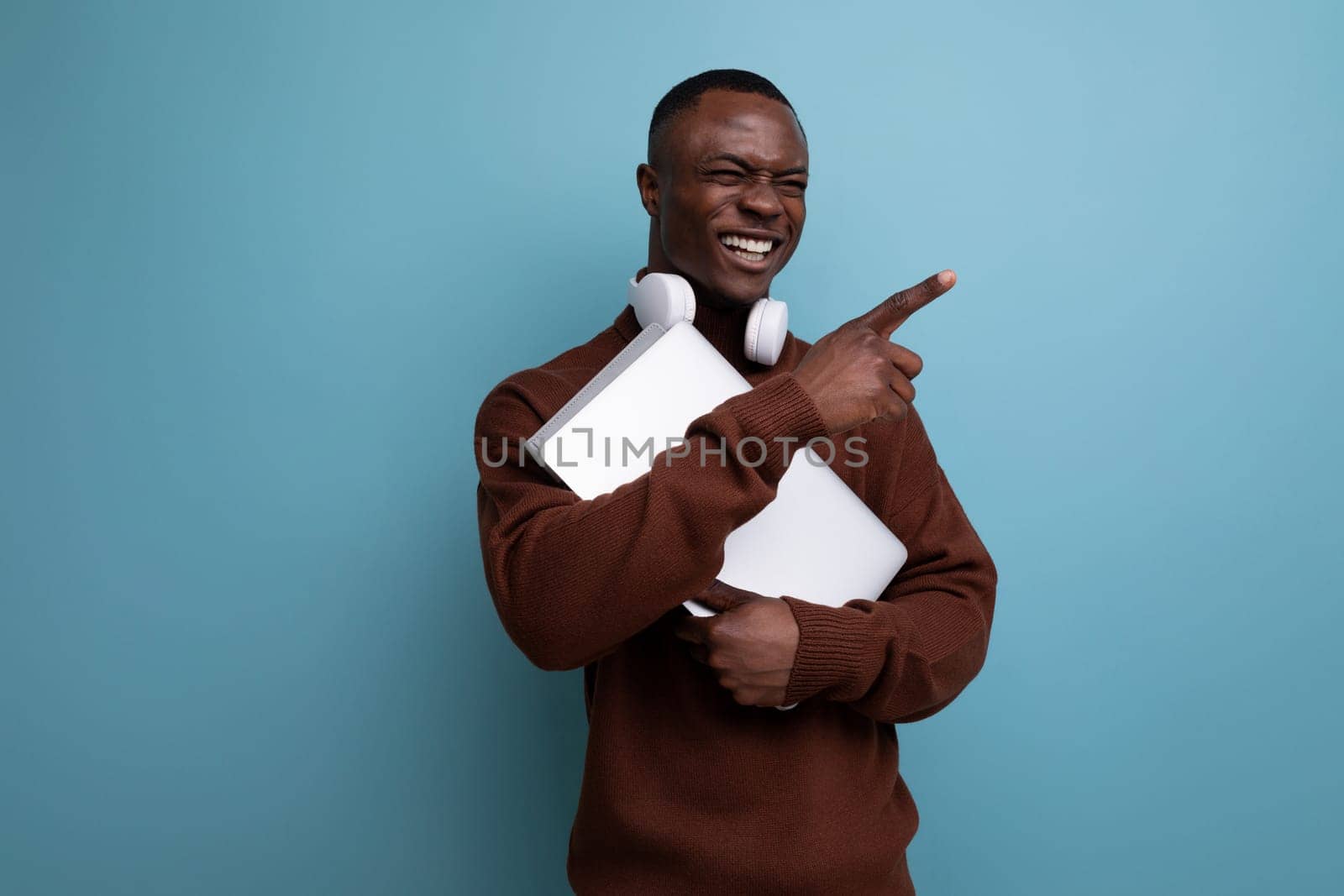successful young american student with laptop and headphones on background with copy space.