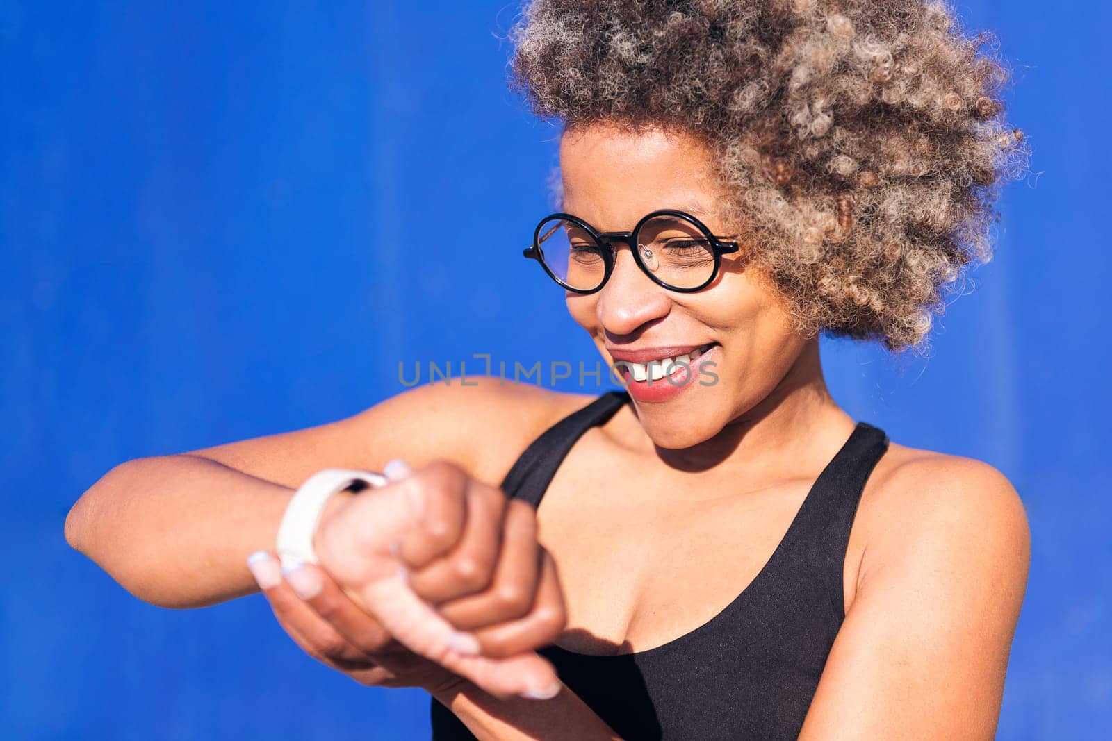 sporty african woman looking at smart watch by raulmelldo