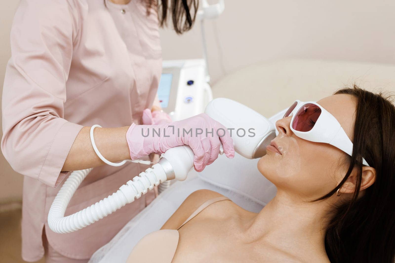 Therapist beautician makes a laser treatment to young woman's face at beauty SPA clinic. Facial laser hair removal epilation procedures. Skin care, cosmetic procedures by uflypro