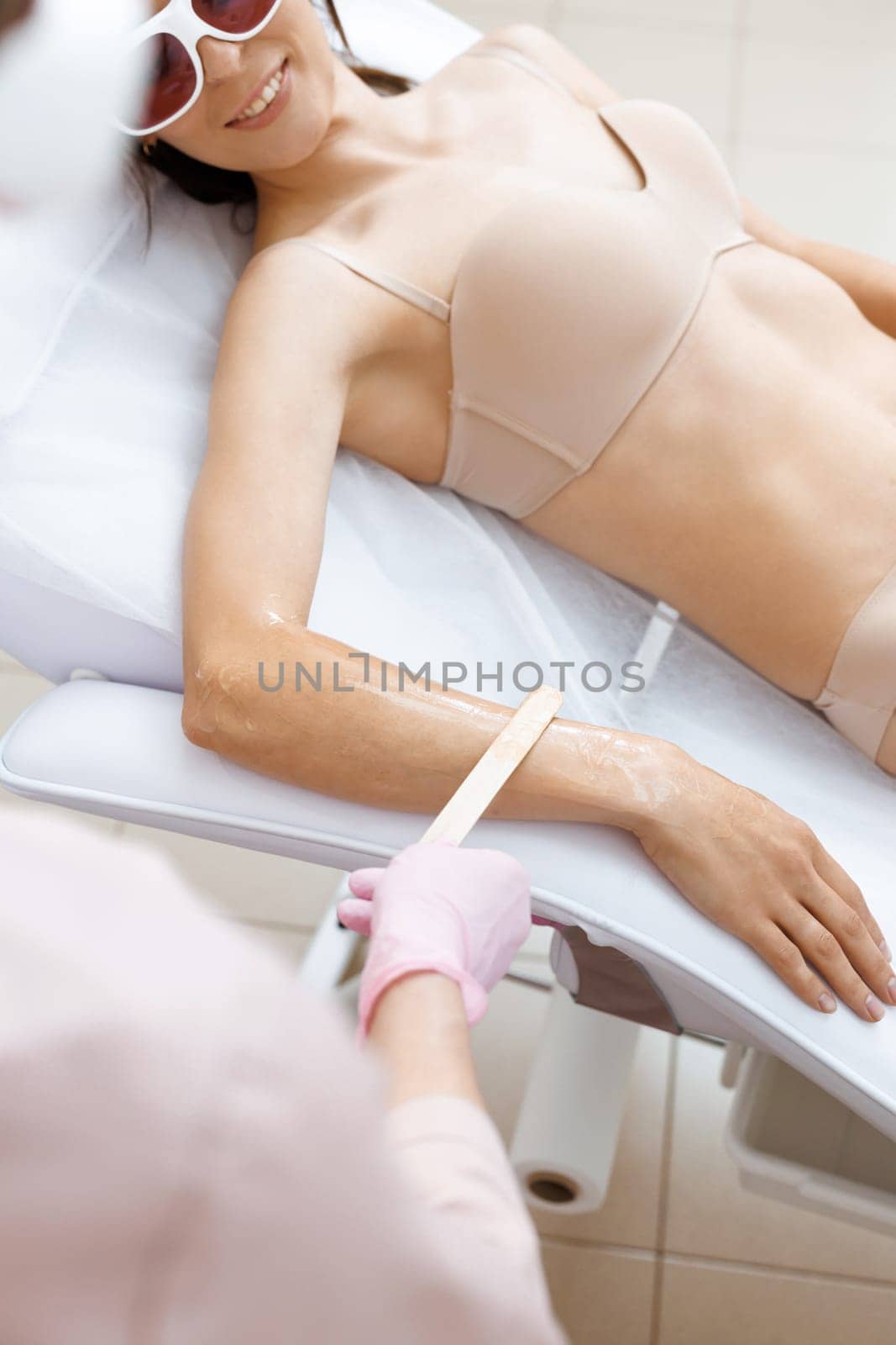 Beautician applying gel on female hand before epilation. Cosmetologist preparing woman skin for laser hair removal treatment in cosmetology clinic. Master applies special gel to the hands of woman.