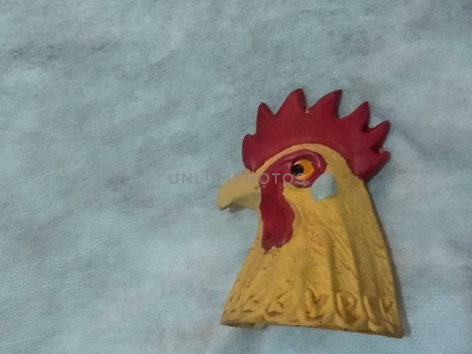 ceramic figurine of a rooster head on a gray background, handmade bell. High quality photo