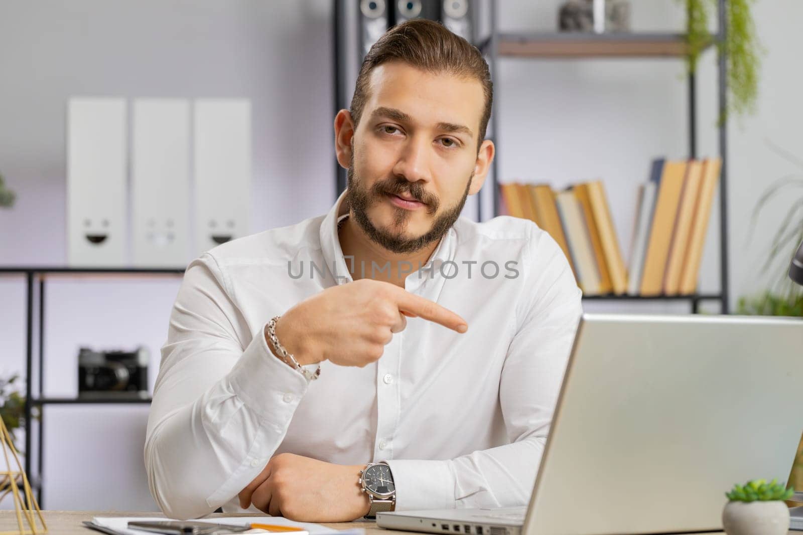 Business man working online on laptop, finishing work, positive feedback, like, approving application, good offer sale advertisement. Freelancer guy at office workplace looking at camera, talking