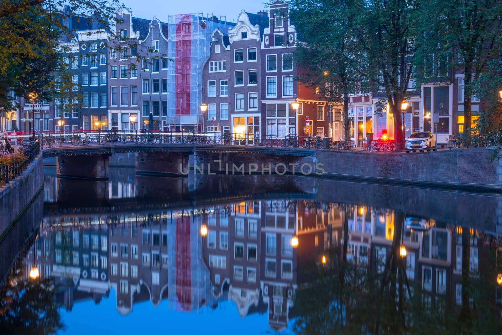 Netherlands. Stone banks and a bridge over the Amsterdam Canal. Lots of parked bikes. Morning reflections in the water before dawn