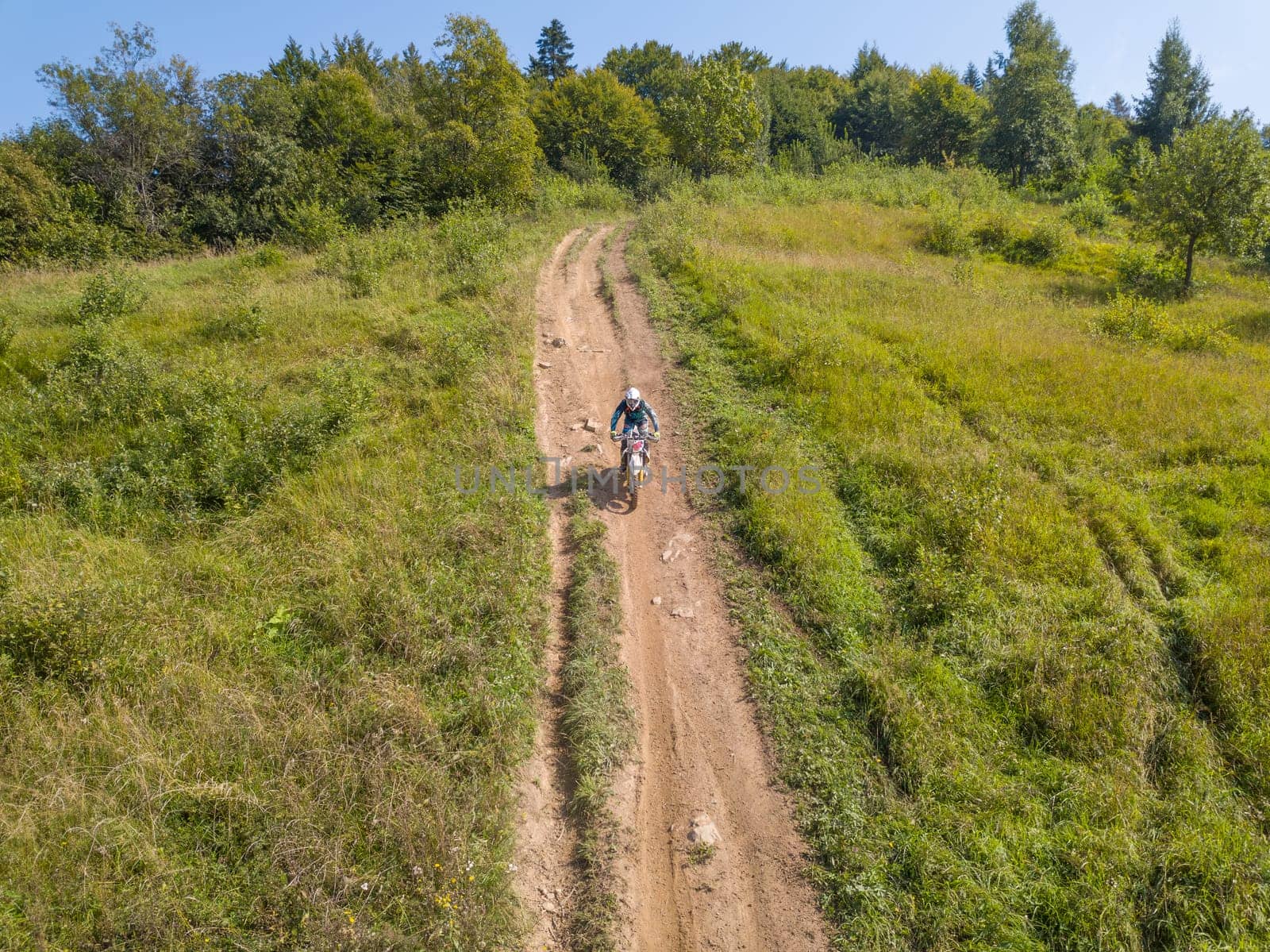 Enduro athlete on the forest path on a sunny summer day. Aerial drone view