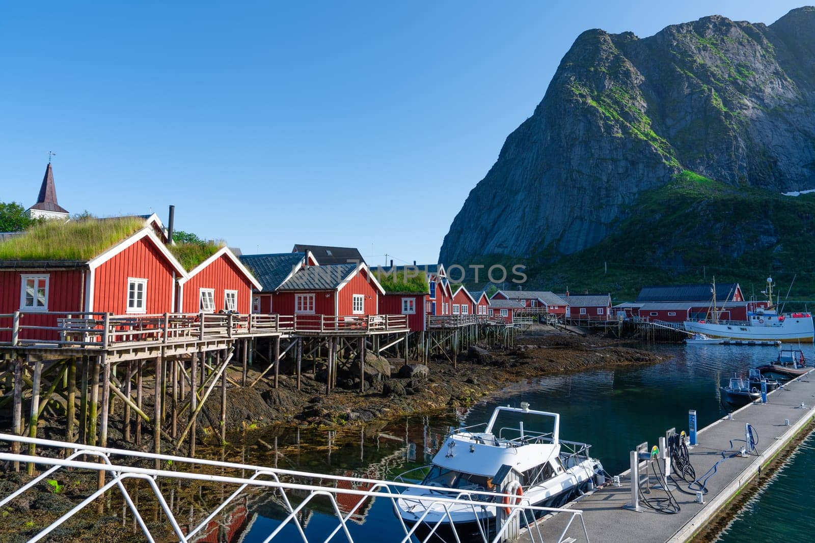 Summer in Reine, Lofoten Islands, Norway. Popular tourist destination. Old fishermans village with wooden red cottages by PhotoTime