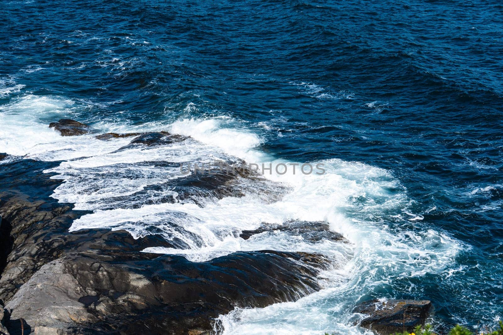 The deep blue Ocean with waves crashing on a rocky island. rugged, rocky coastline at the Sea by PhotoTime