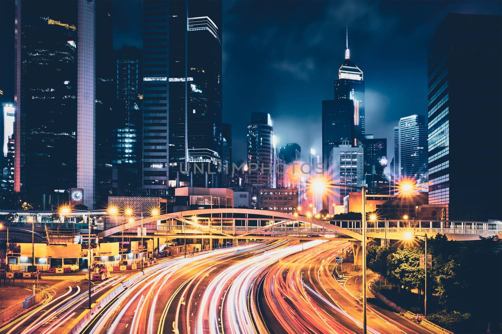 Street traffic in Hong Kong at night. Office skyscraper buildings and busy traffic on highway road with blurred cars light trails. Hong Kong, China
