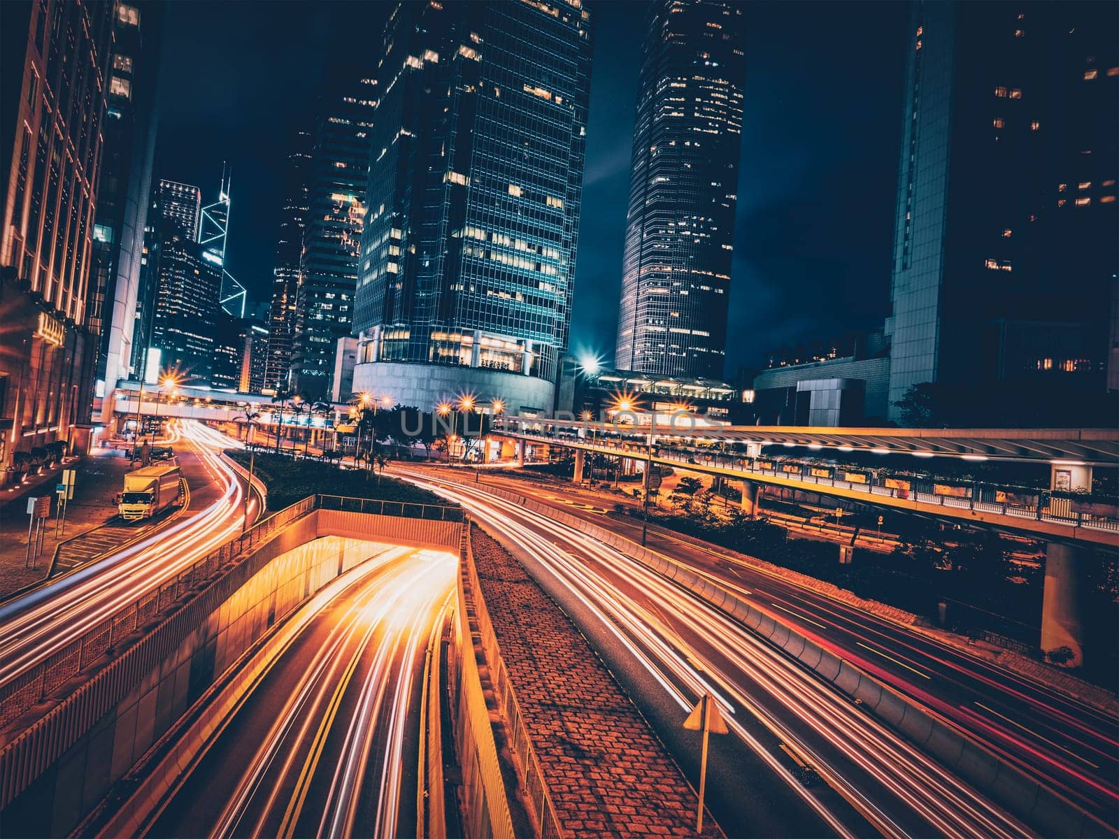 Street traffic in Hong Kong at night. Office skyscraper buildings and busy traffic on highway road with blurred cars light trails. Hong Kong, China